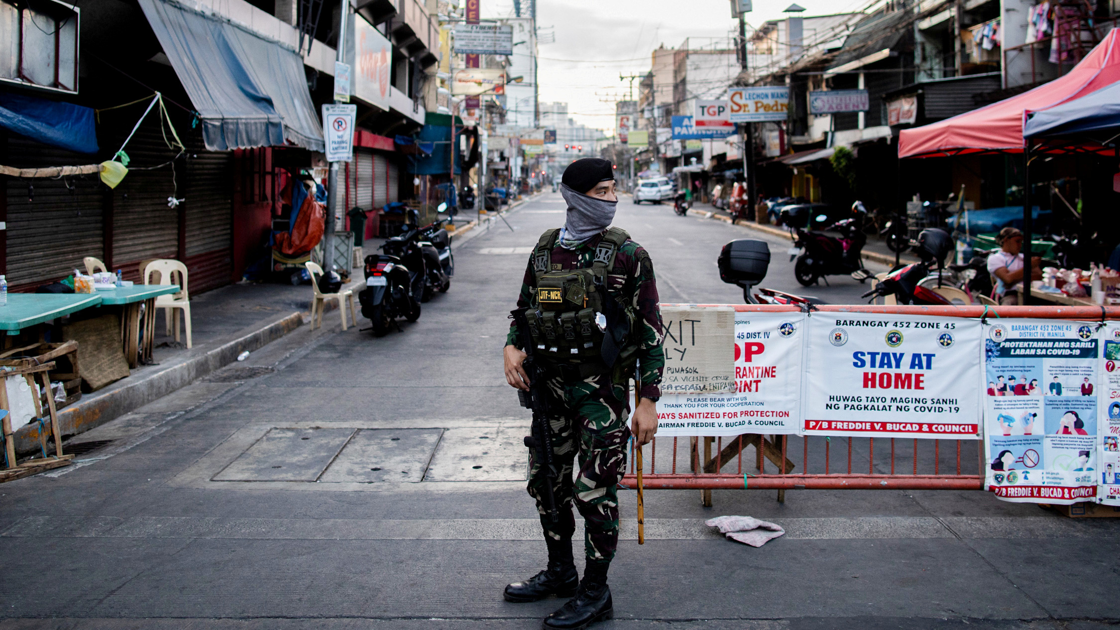 The photo shows a soldier on an empty street in a busy district.