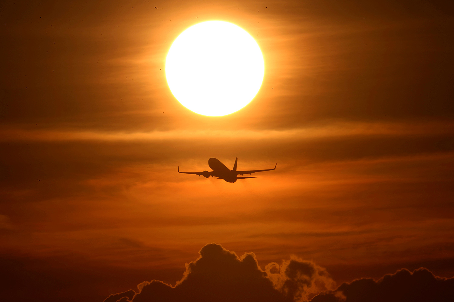 The photo shows a plane flying into the sunset.