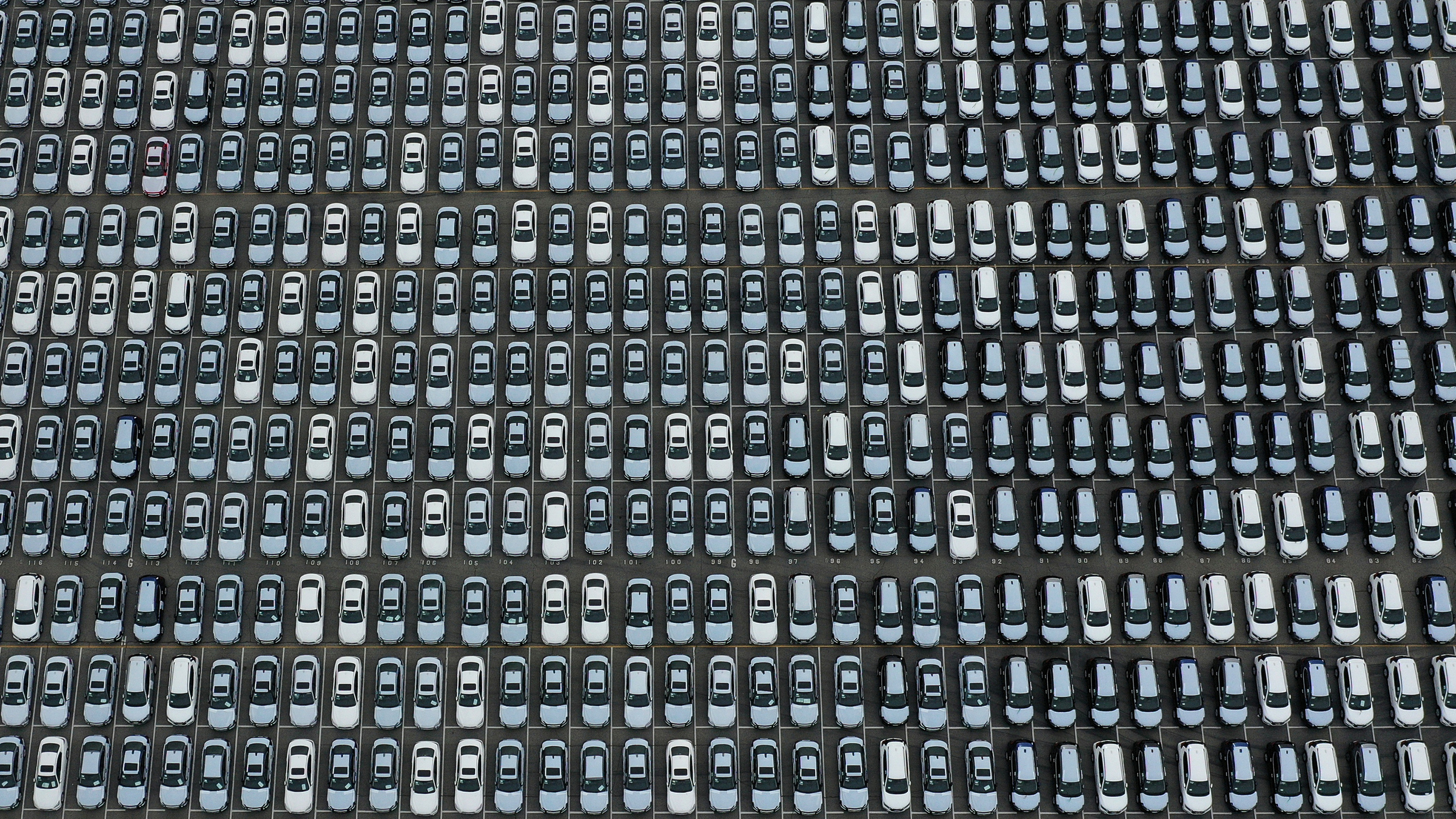 The photo is an aerial shot of a large lot packed completely with lines of cars.
