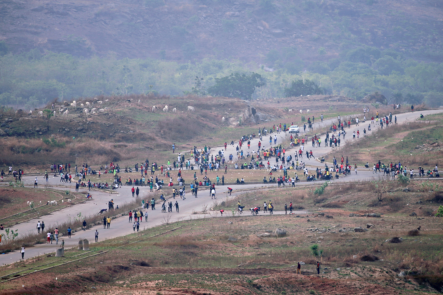 The photo shows a crisscrossed country road from a great distance with an immense crowd of people moving through the crossroads.