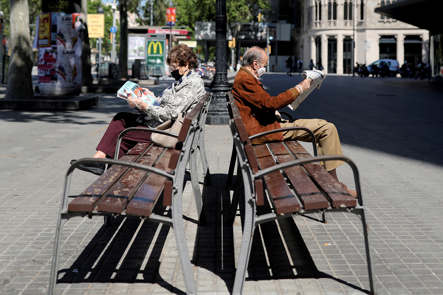 The picture shows two people on benches facing in opposite directions.