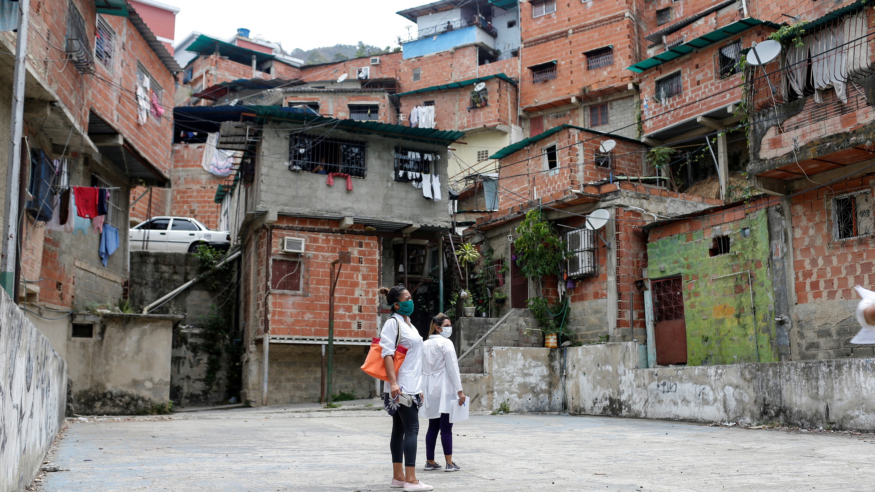 Picture shows two people standing before a huge neighborhood of towering ramshackle structures.