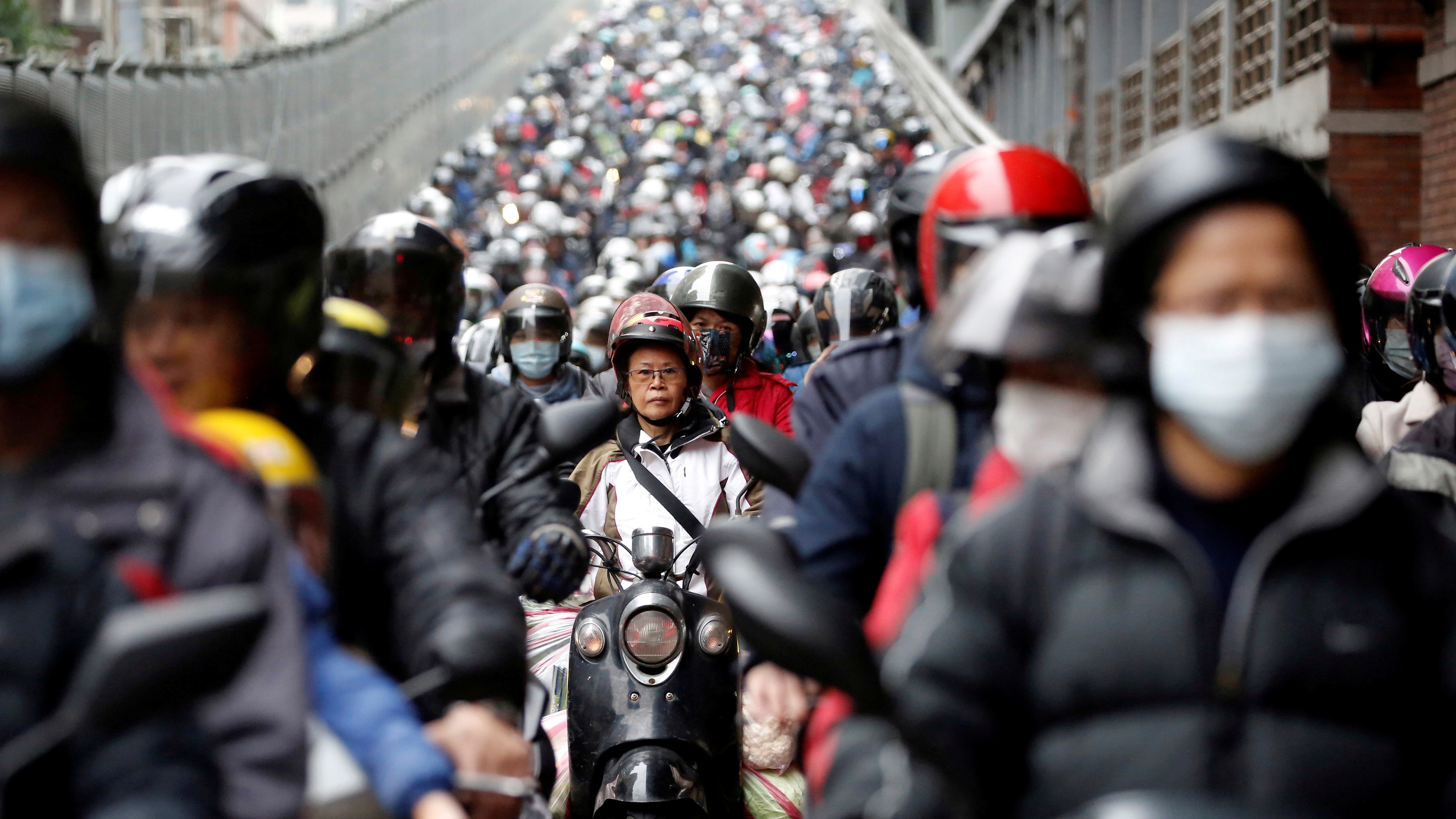 The photo shows a wide avenue filled with motorcycles heading toward the camera lens.