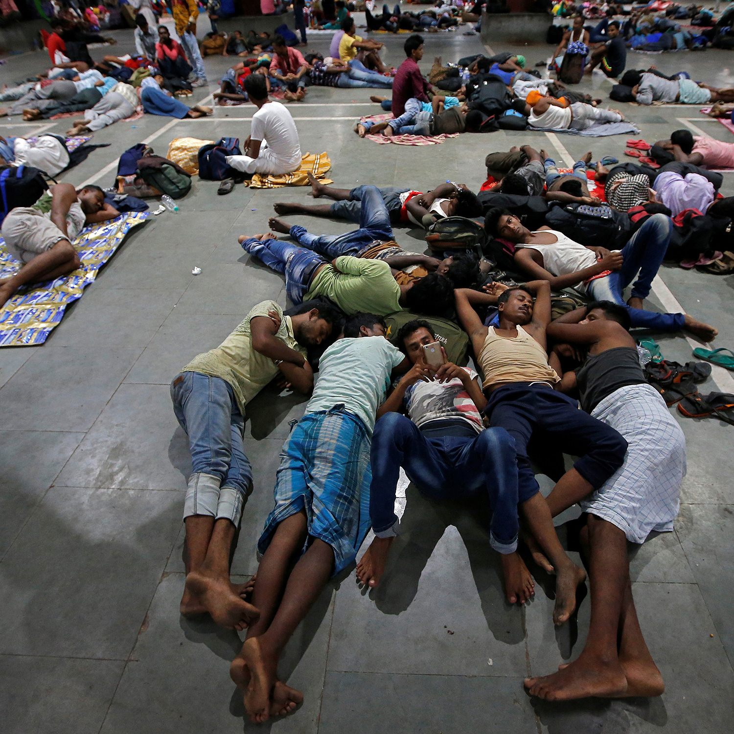 The photo shows a large number of people stretched out on concrete resting.