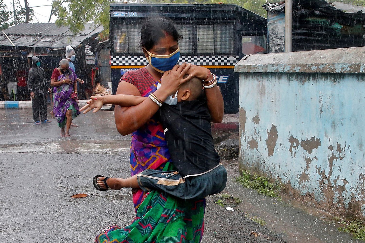 The photo shows a woman ruching down the street in a heavy rain while her boy clings to her.