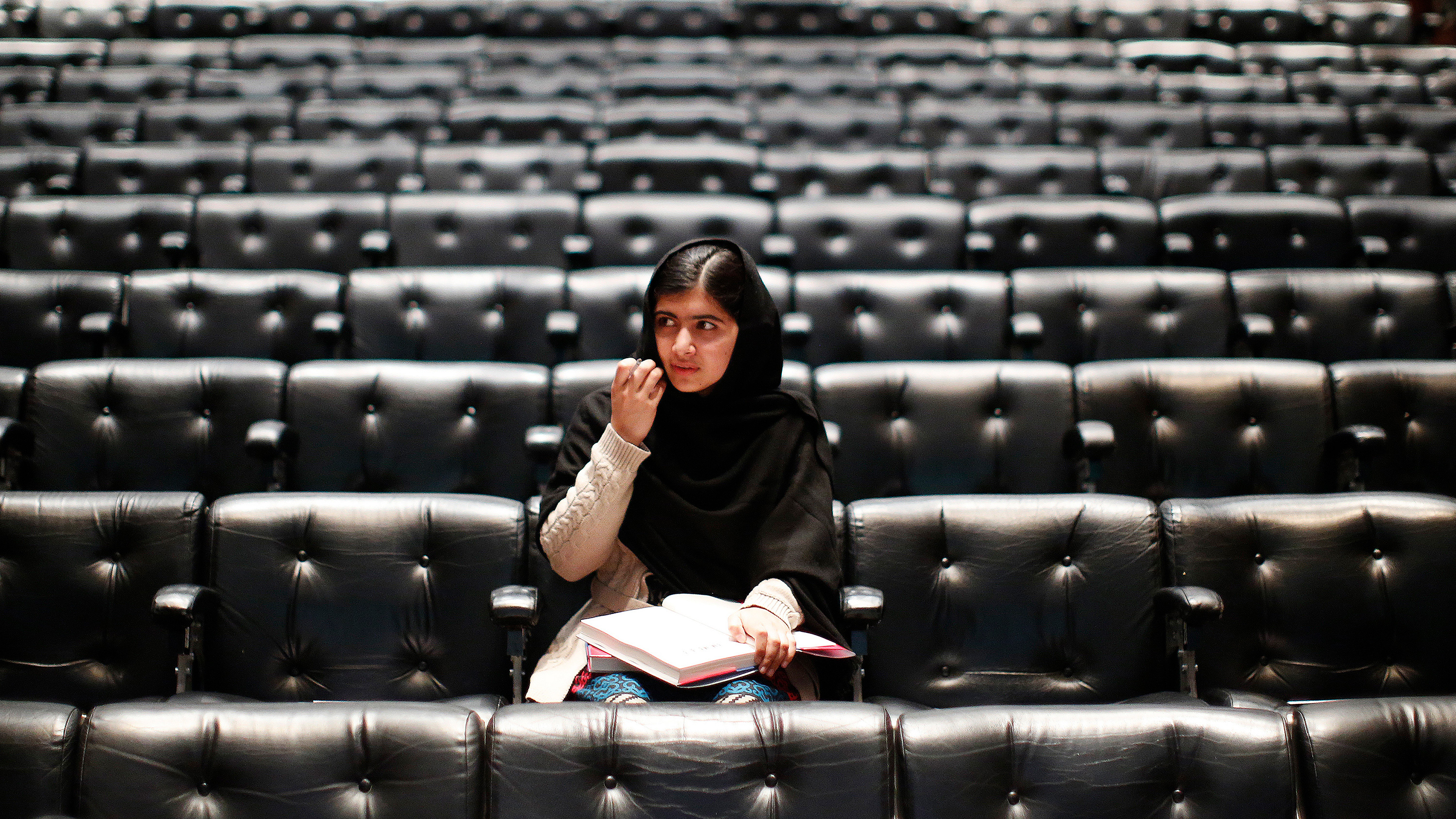 The photo shows Malala in an empty auditorium seated where the audience will sit to listen to her.
