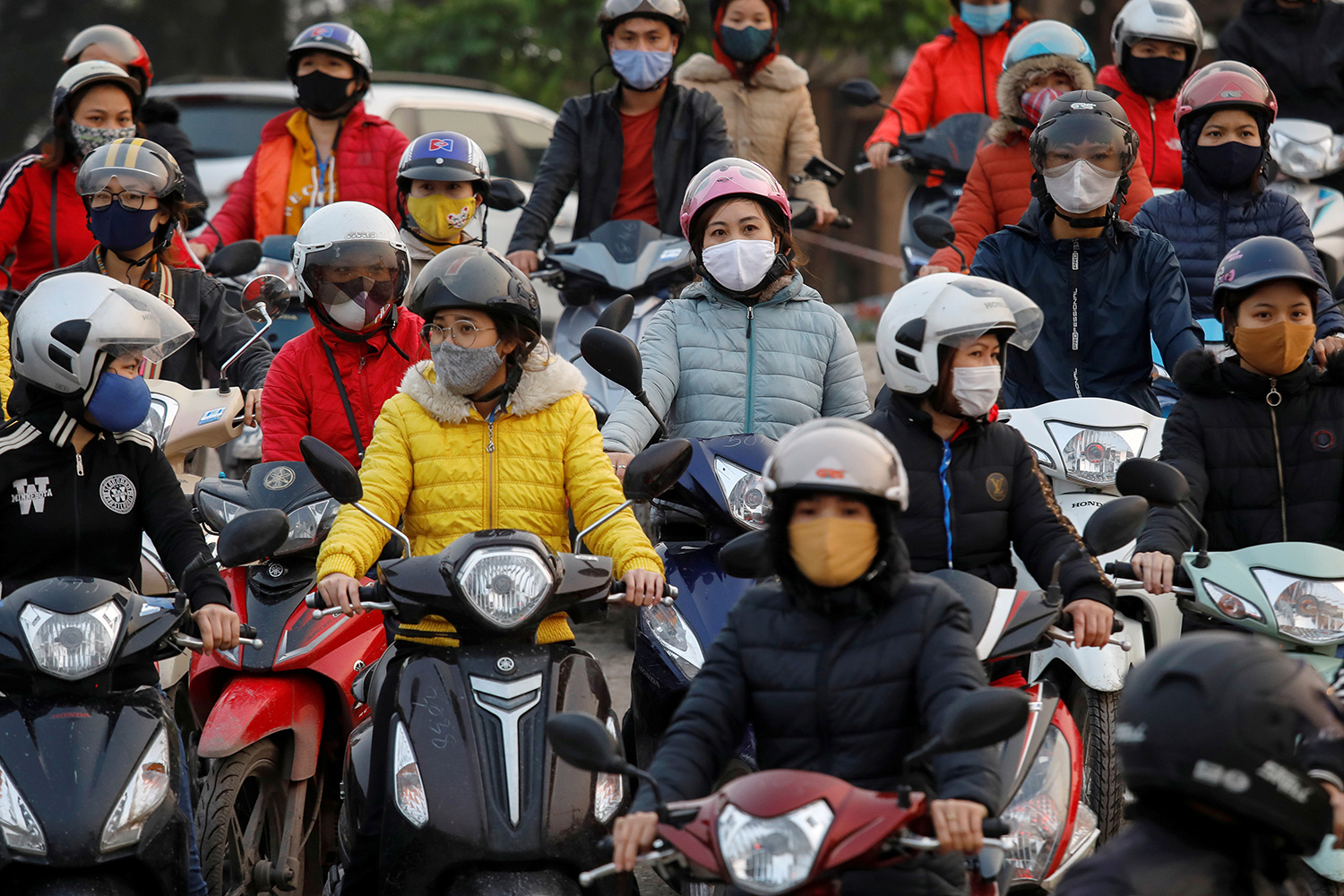 The photo shows a number of people on motorcycles wearing masks.