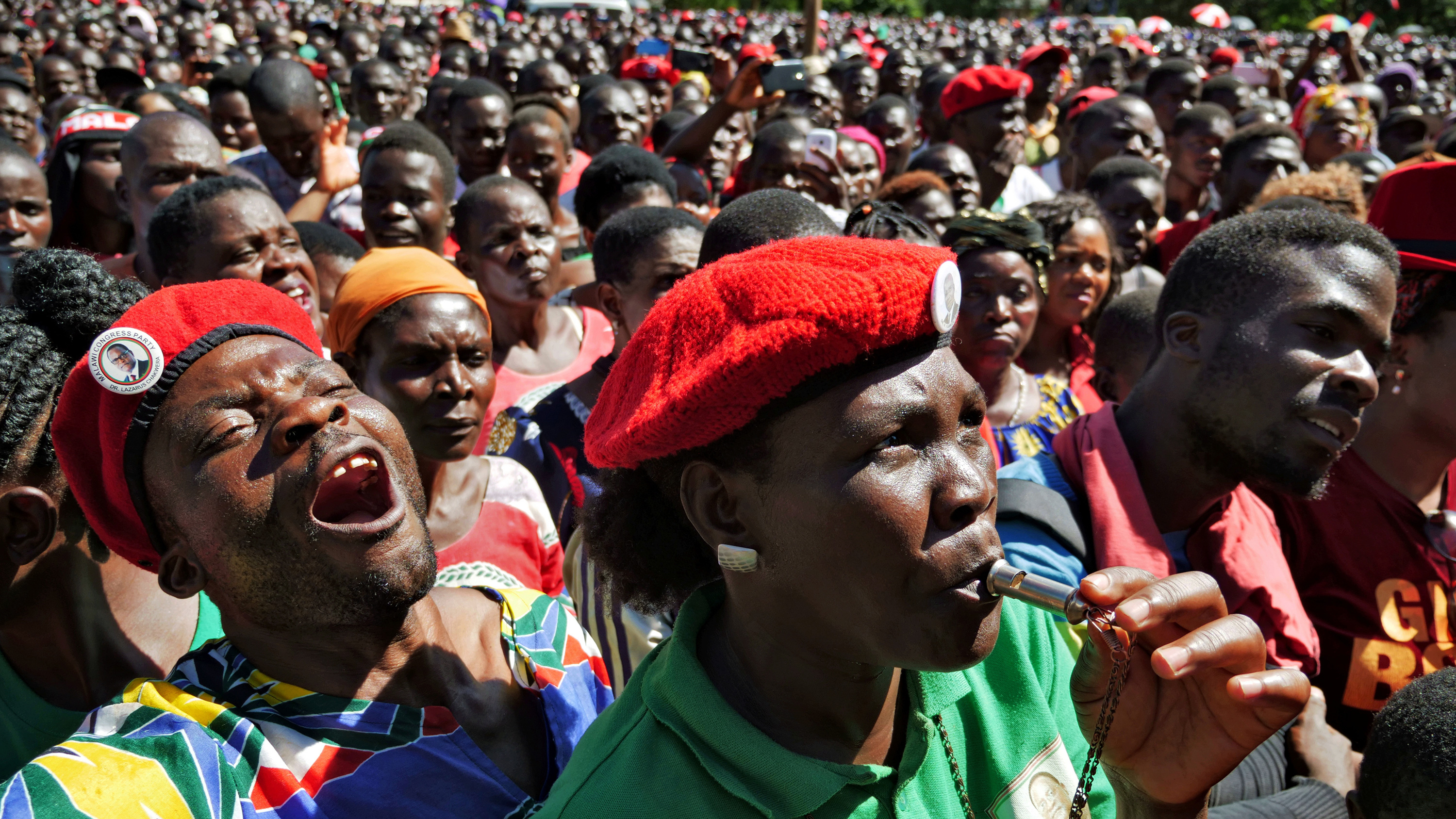 The photo shows a massive crowd with people shouting, blowing whistles, and generally celebrating.