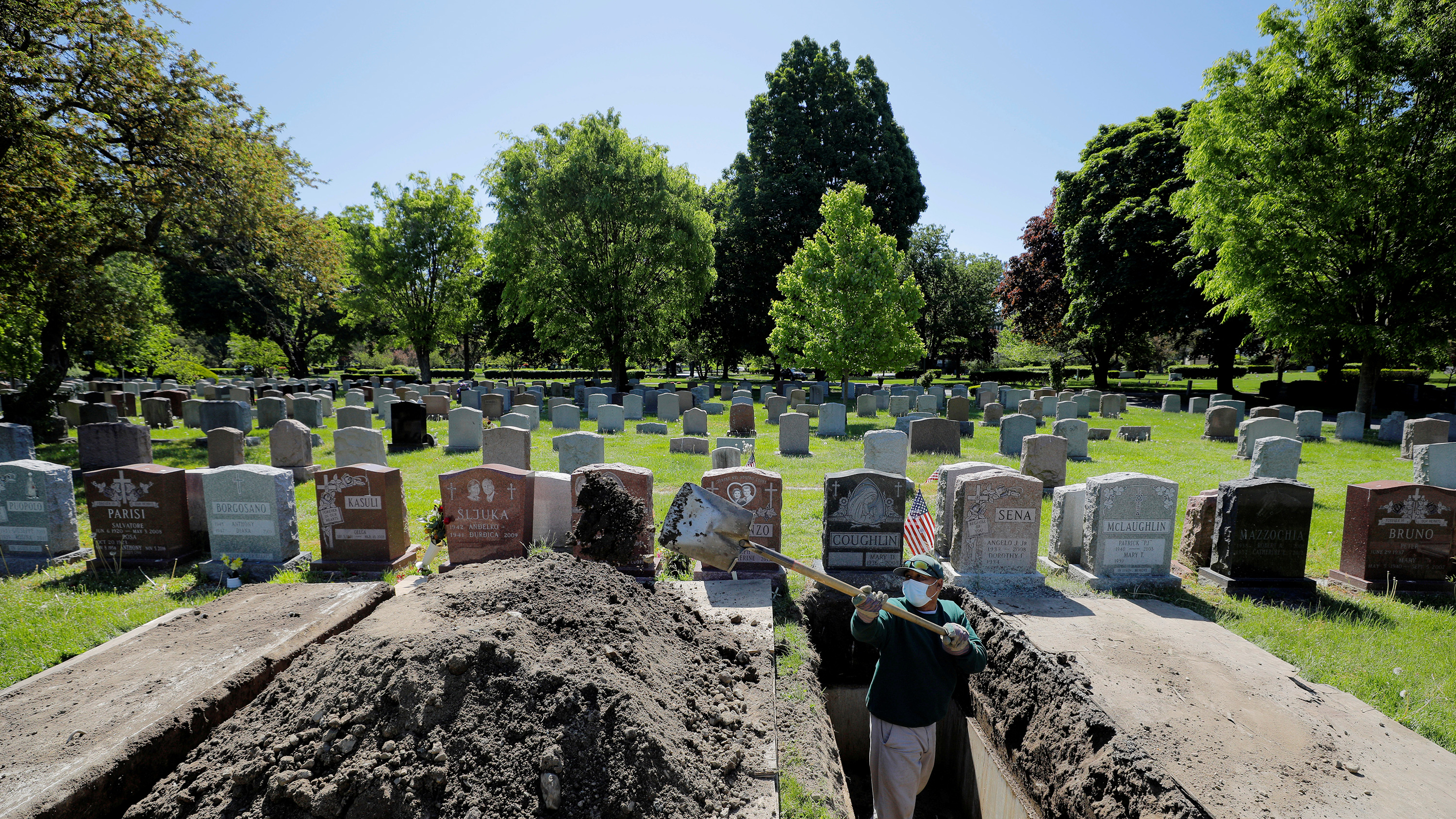 The image shows a cemetery with a grave freshly dug.