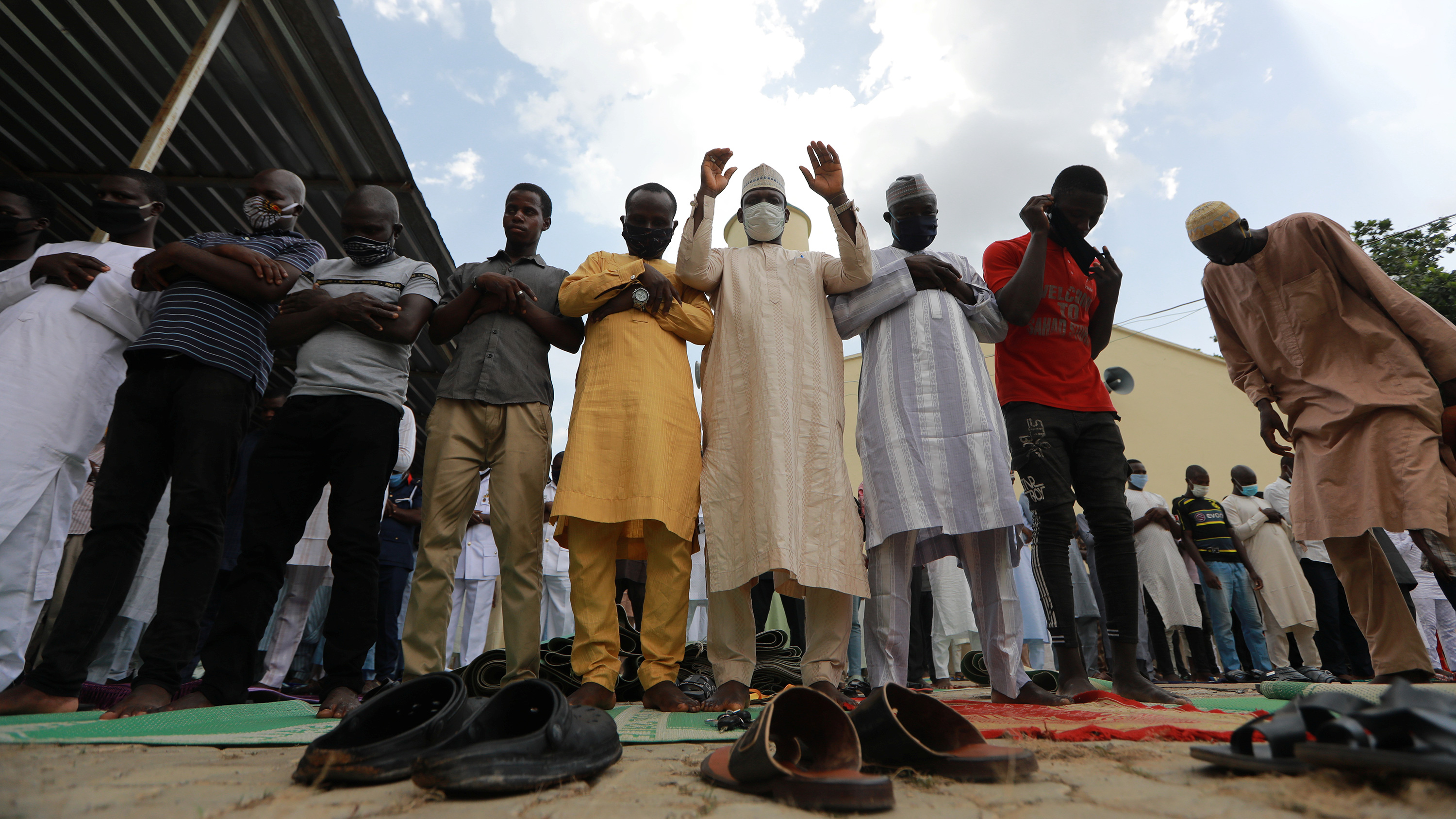 The photo shows a line of muslim men praying.