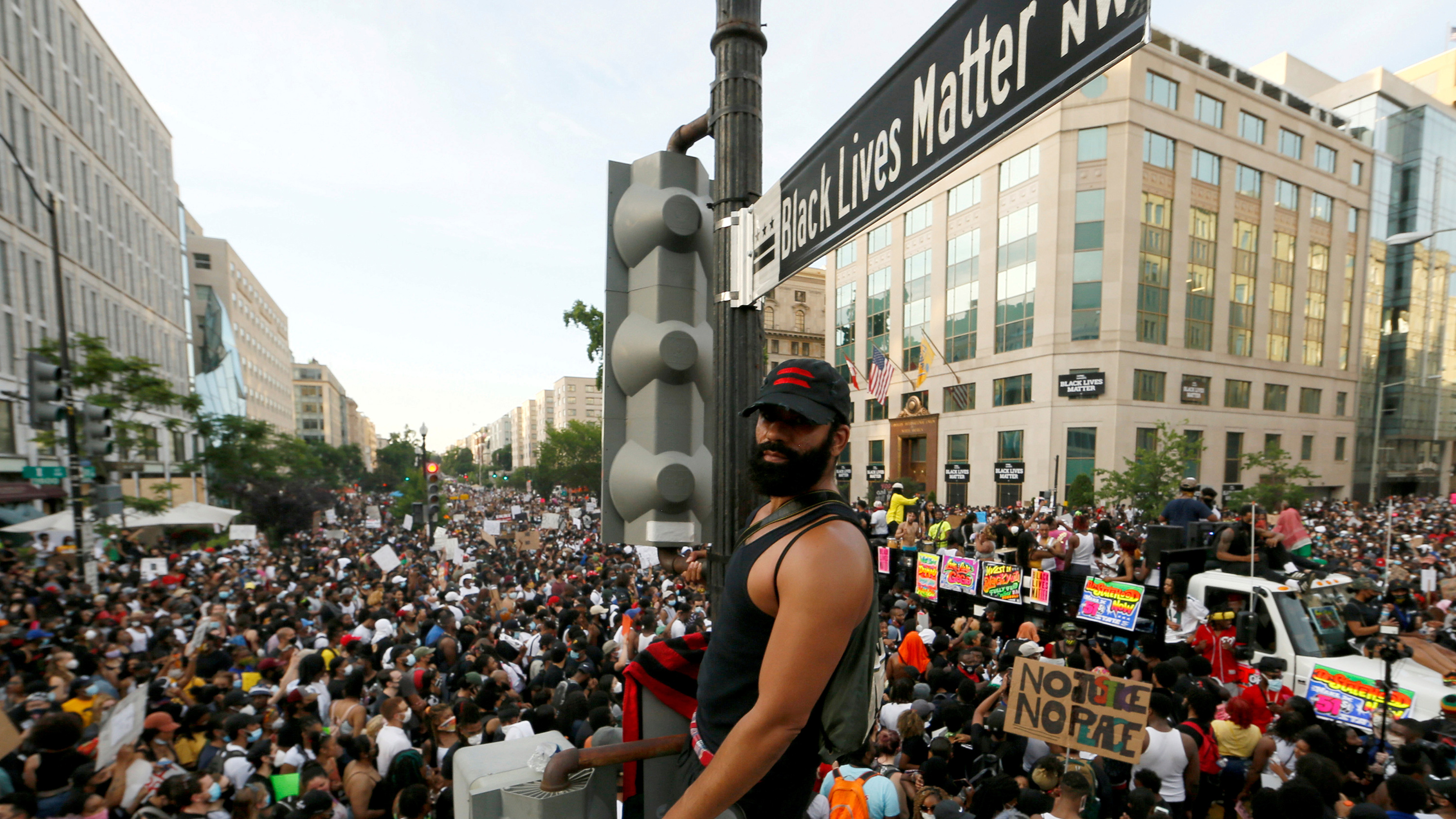 The photo shows the protestor standing on the light post above a massive crowd.