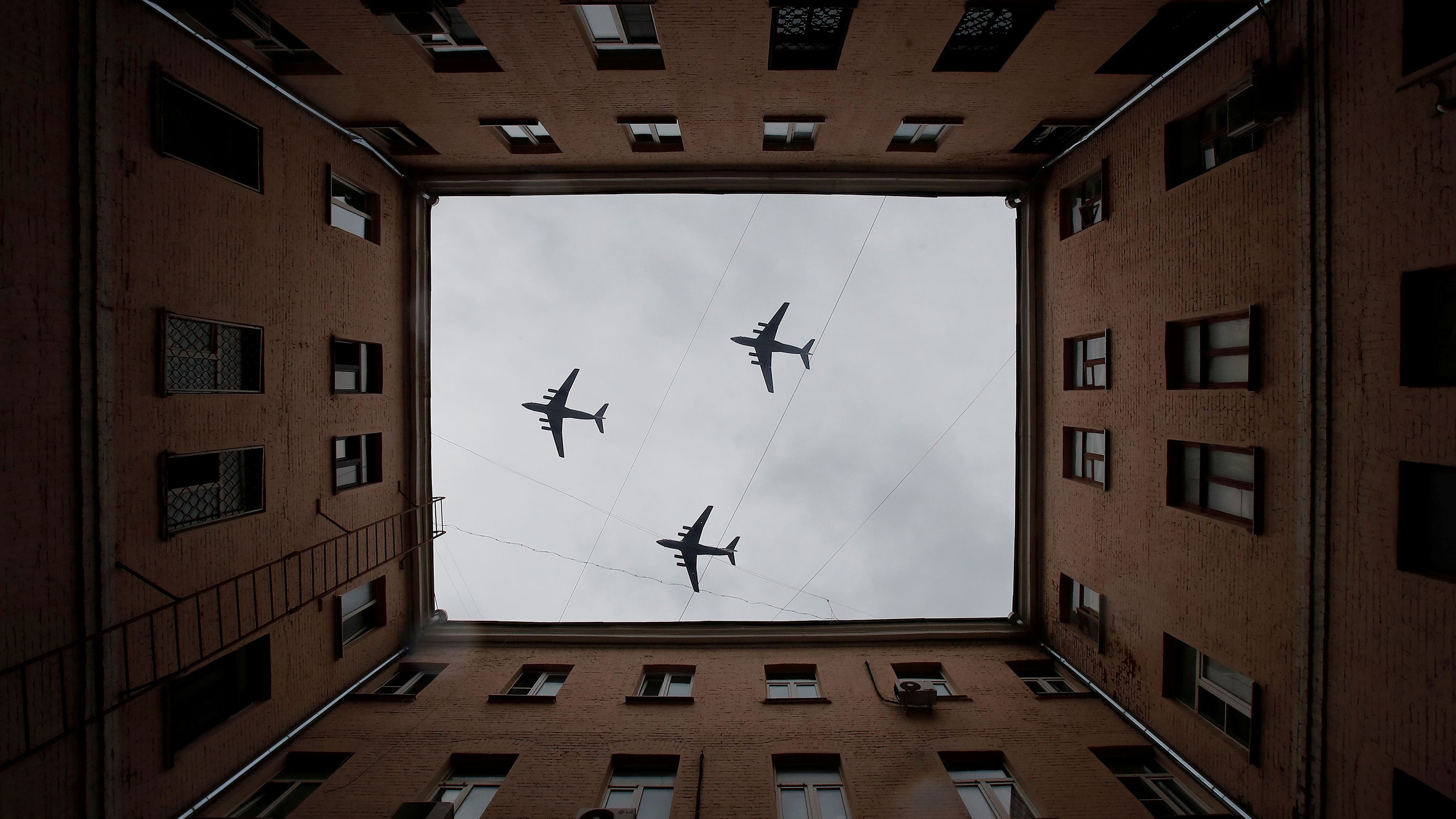 The striking image shows three planes photographed looking up througg the open courtyard of a large apartment-style building.