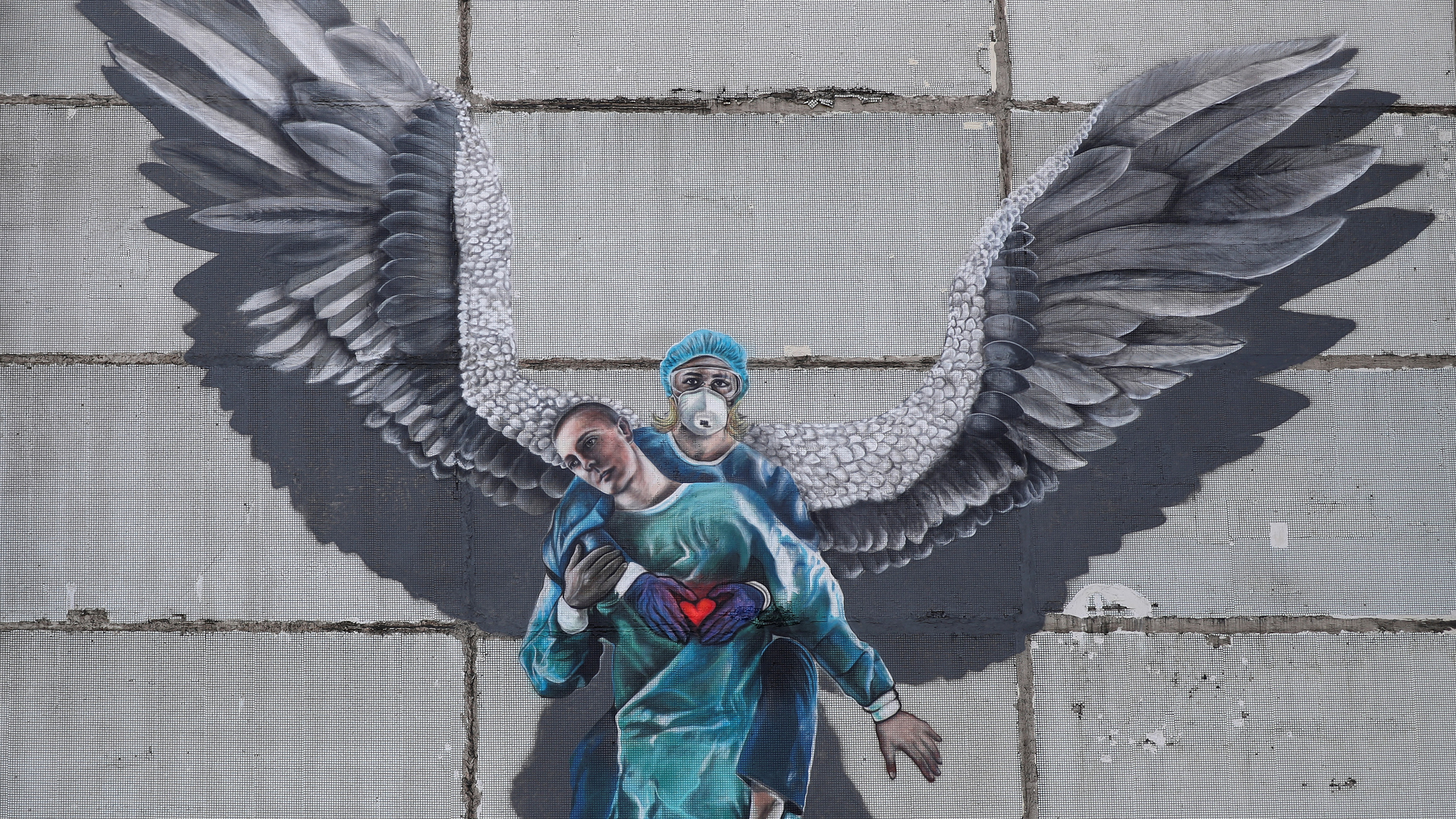 Picture shows a mutal of a health worker with angel's wings lifting another health worker and holding a heart in her hands.