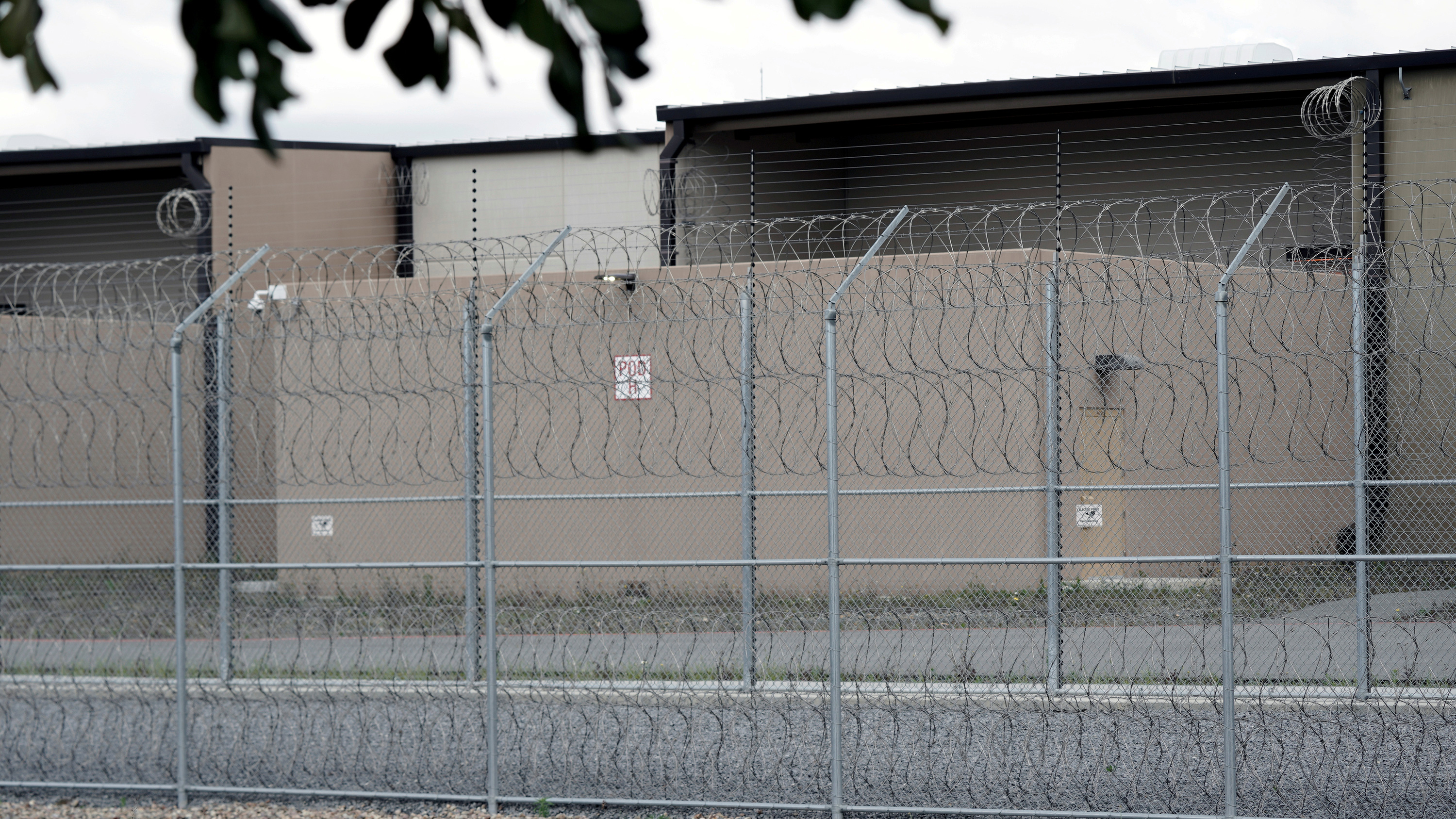 The photo shows a lockup from outside its perimeter barbed wire fence.