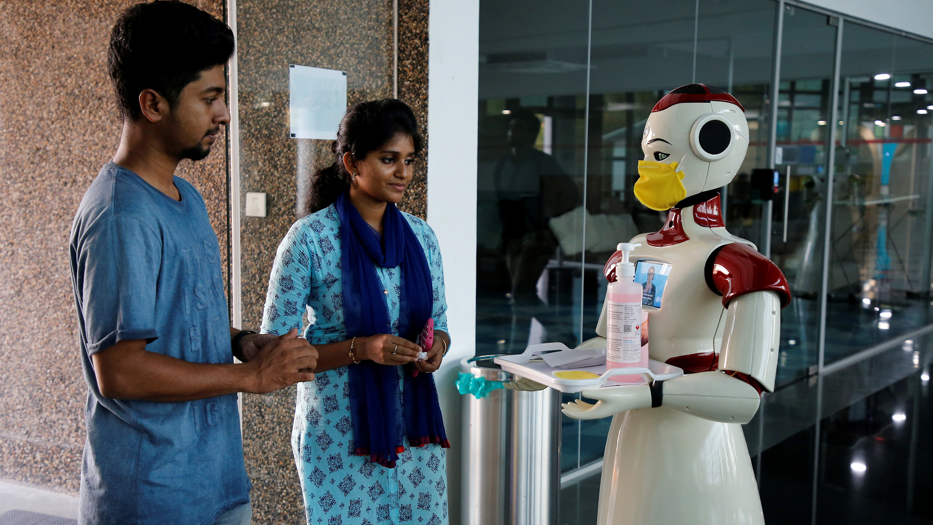 The photo shows two people smiling as they interact with the large, slick robot.