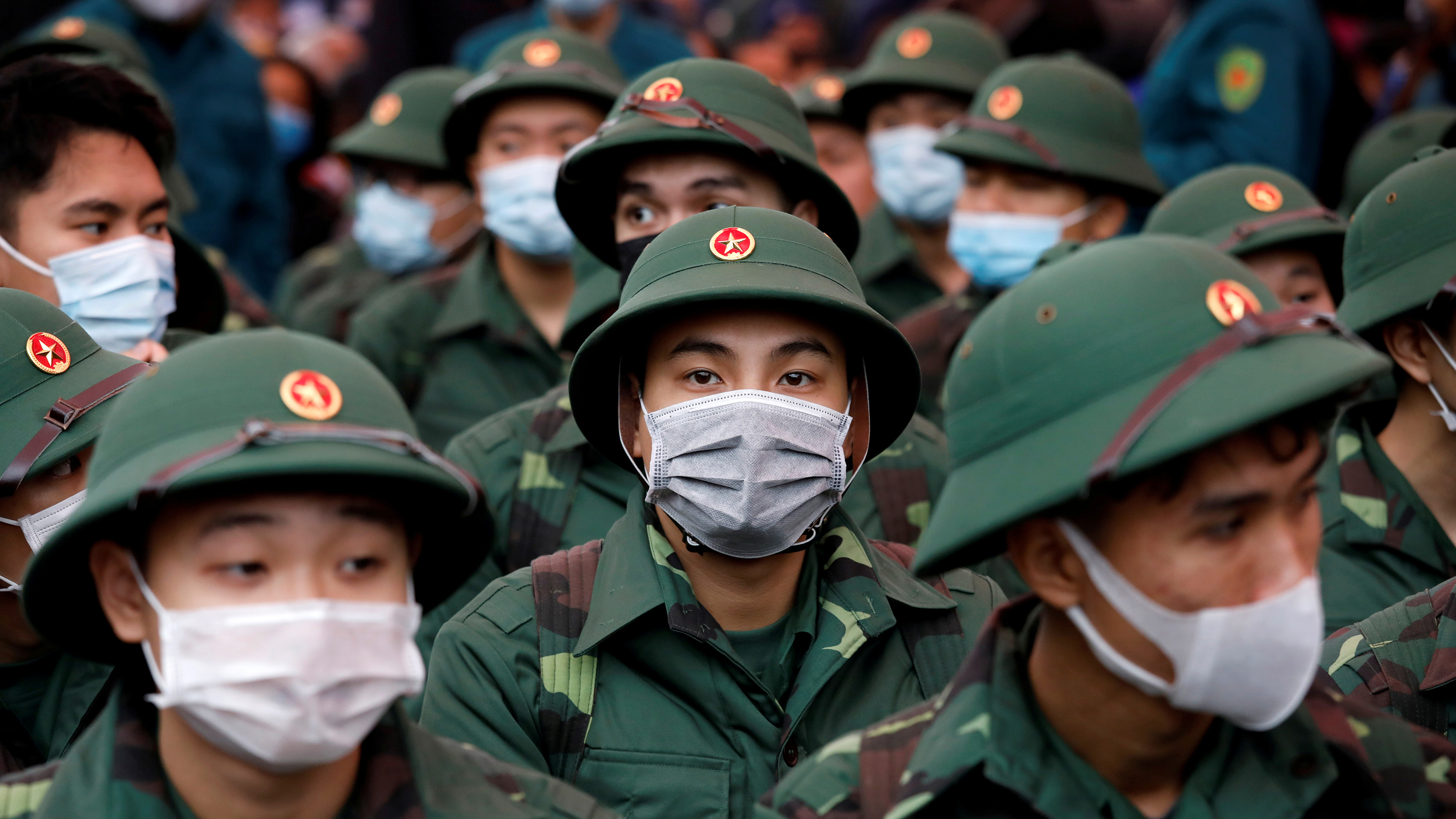 The photo shows a crowd of soldiers in their green dress uniforms all wearing masks.