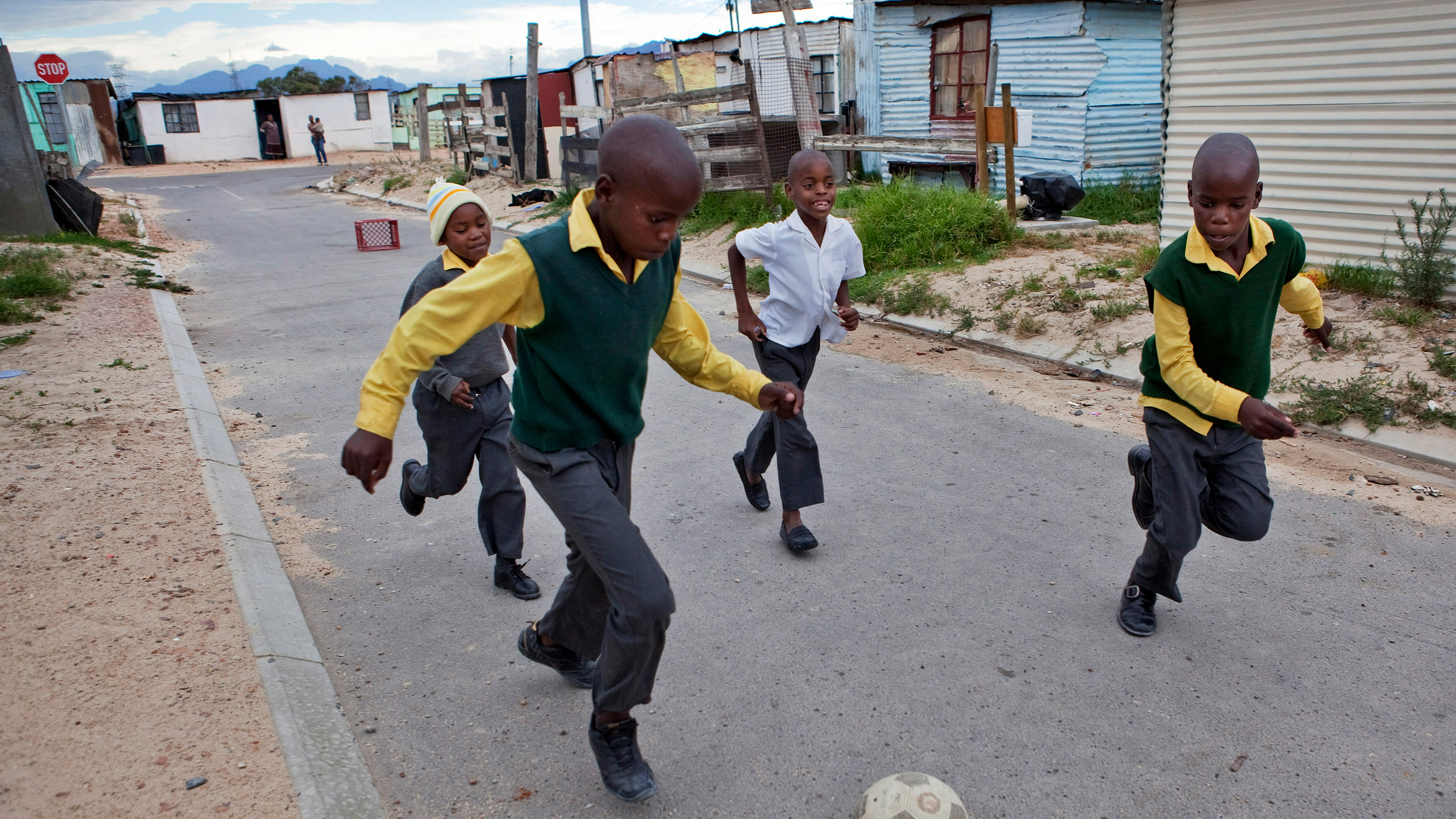 The picture shows a group of small boys running with a soccer ball.