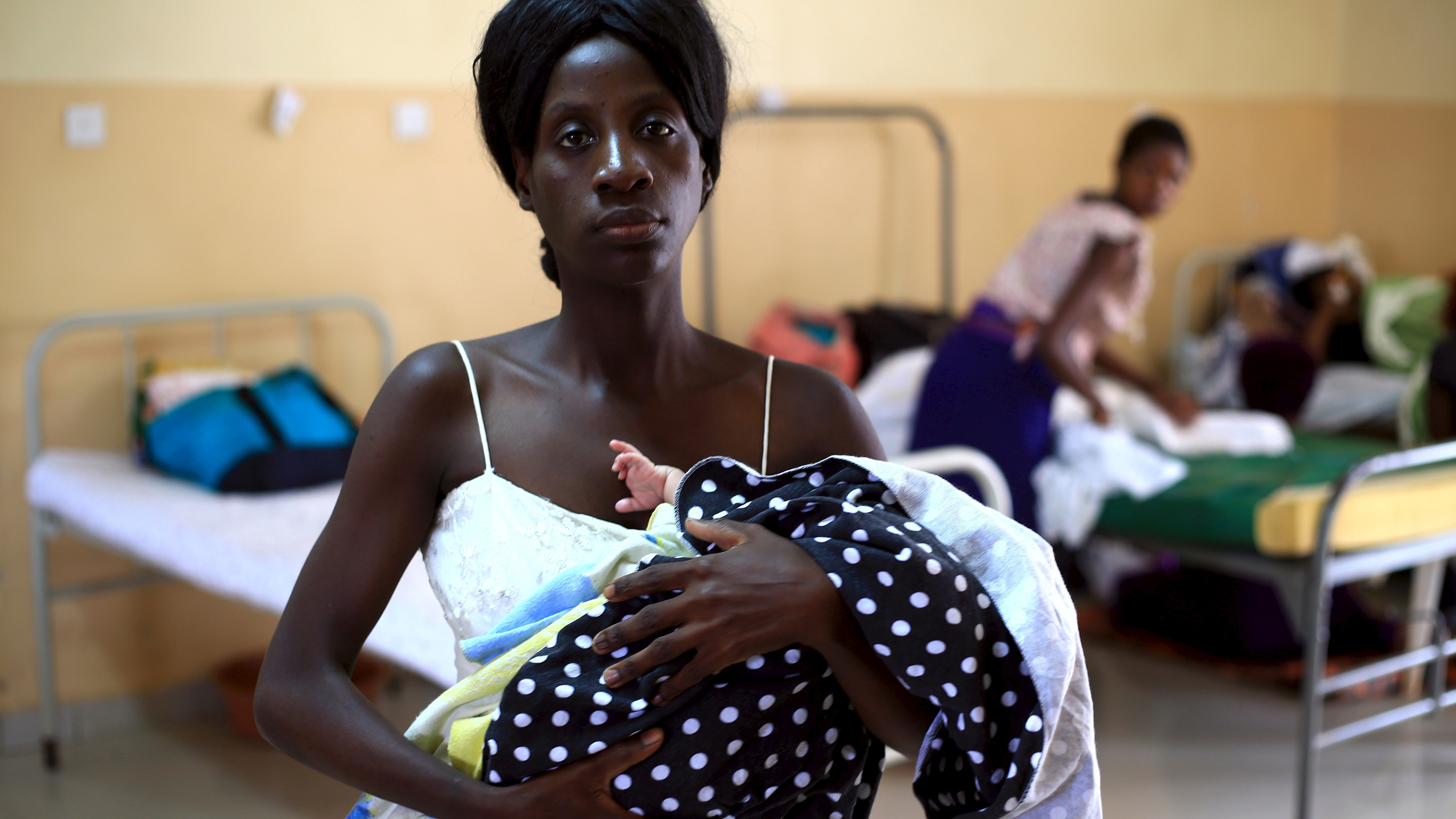 Picture shows the mother holding the baby swadled in blankets. She is looking directly at the camera.