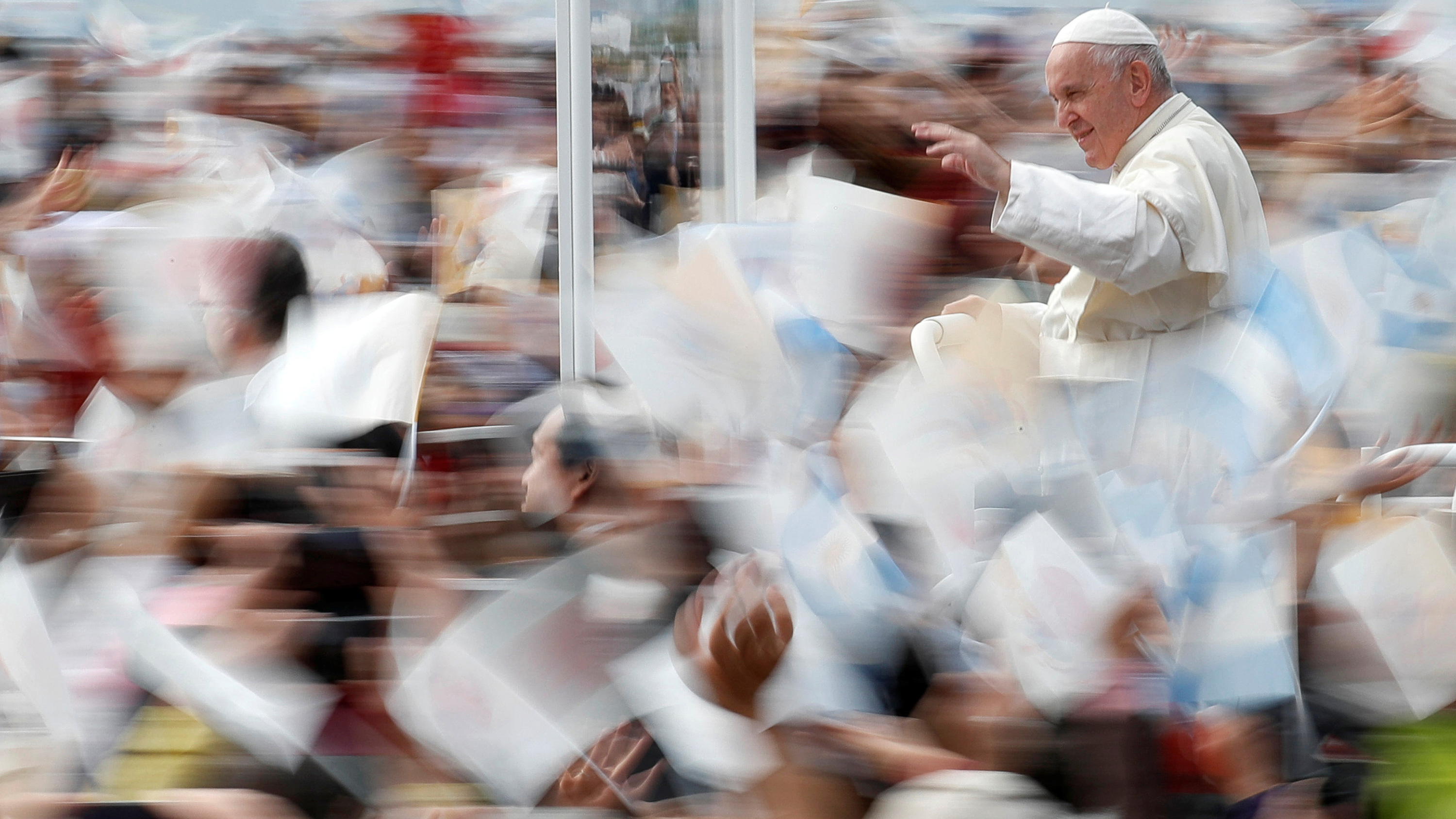The photo shows the pope in clear focus while all the bustling crowds around him are moving and out of focus.