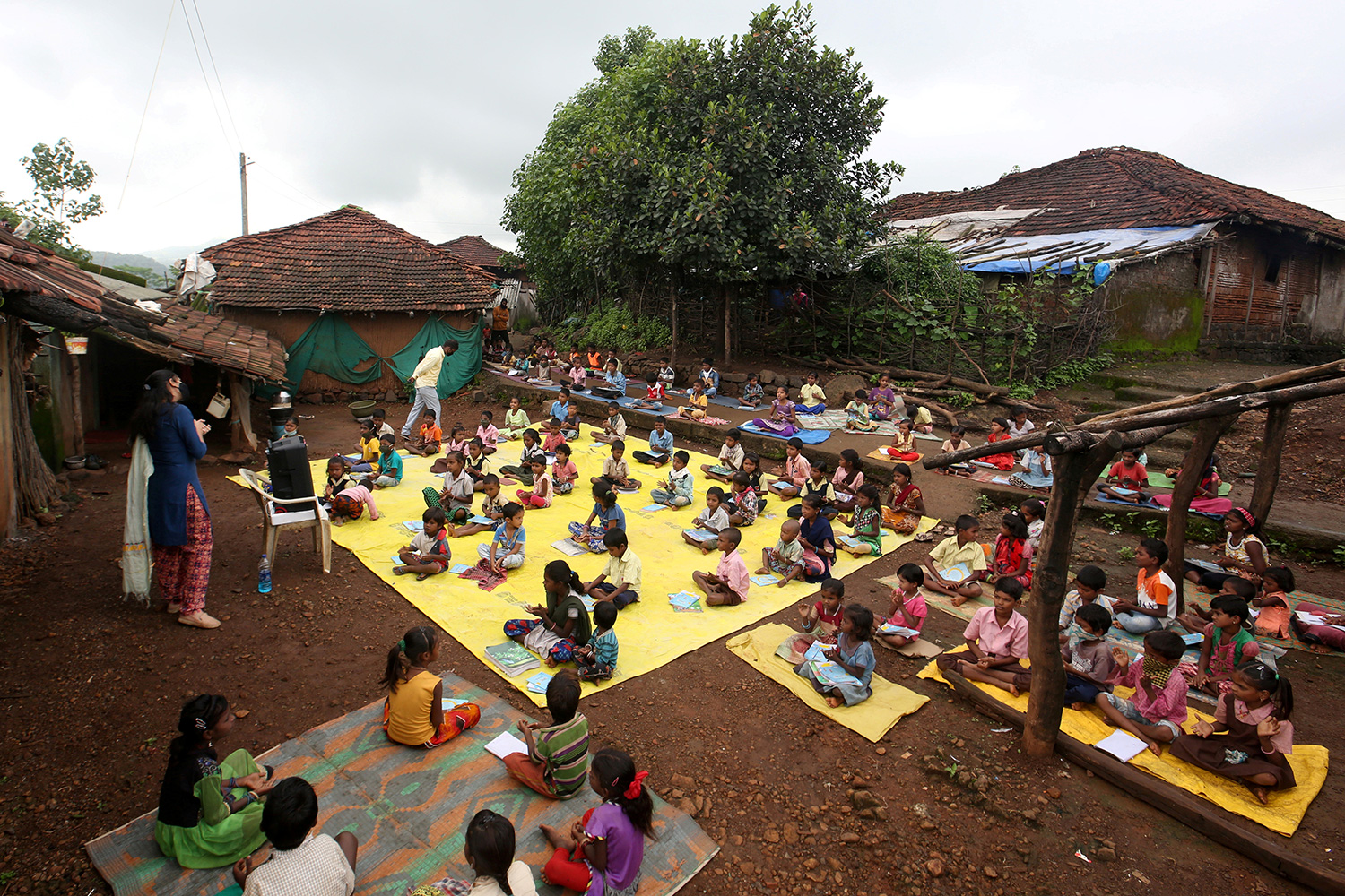Picture shows an outdoor area with a huge group of kids seated at a safe distance from one another.