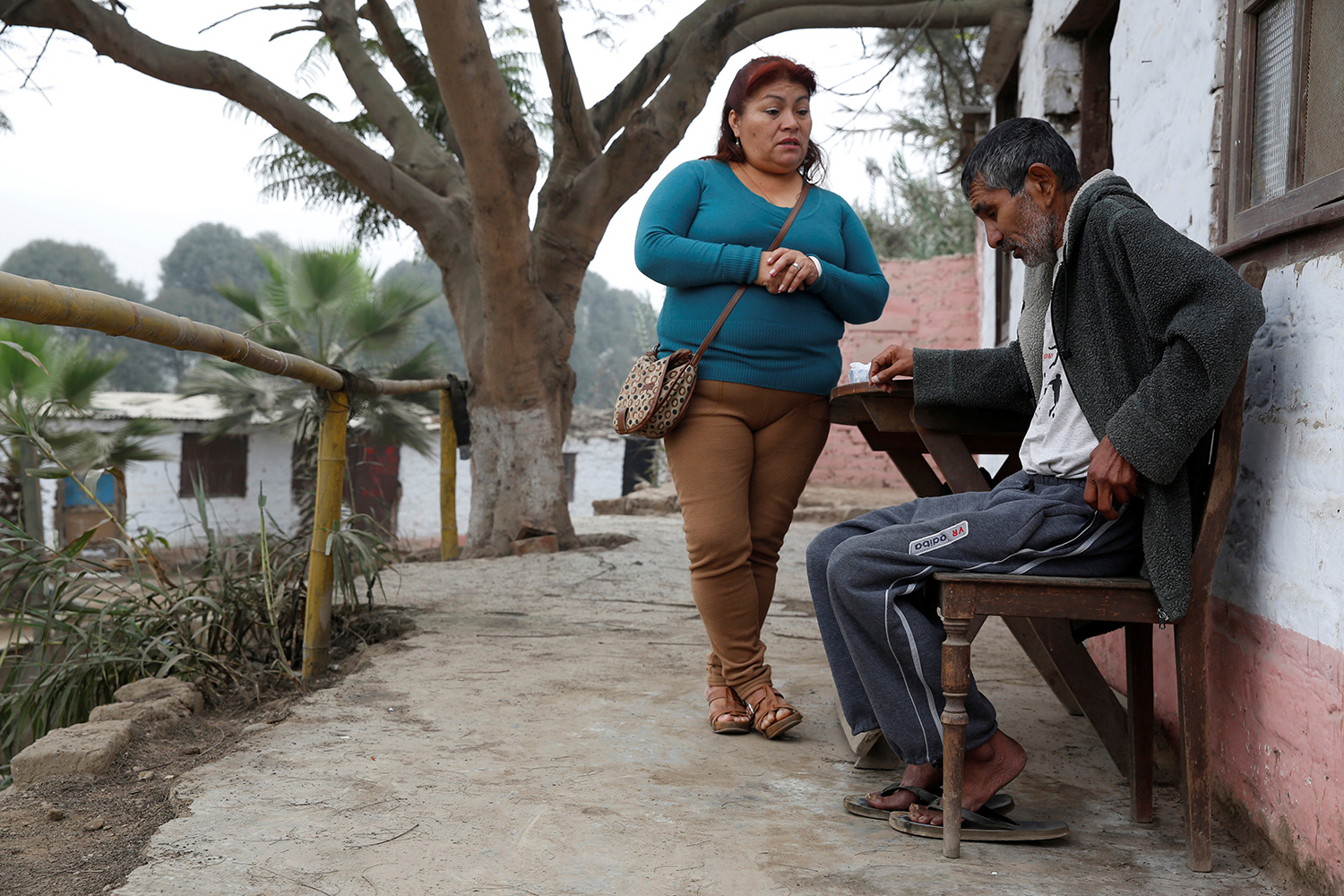 The photo shows the worker standing while the patient is seated in an outdoor setting.