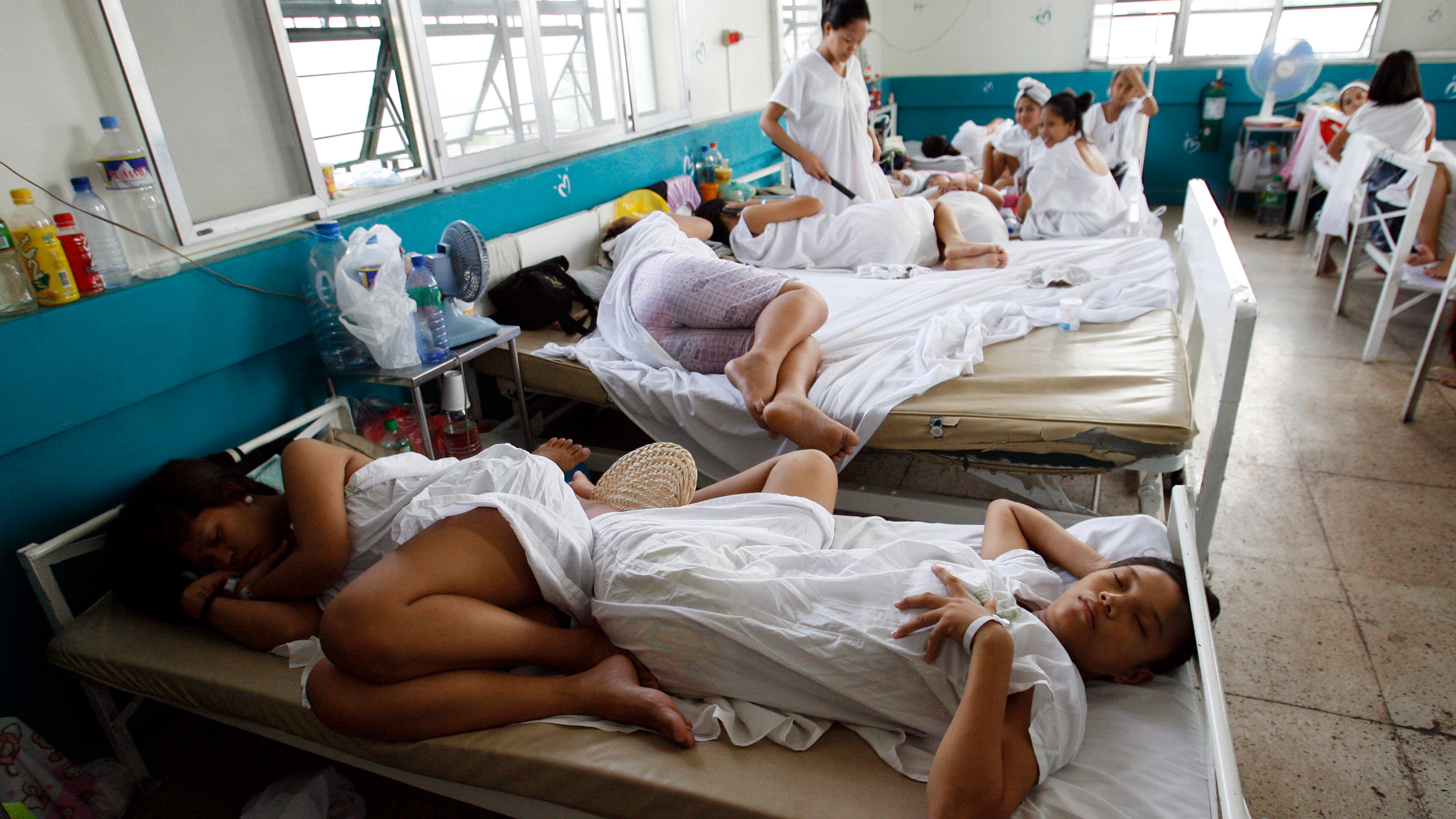 The photo shows a crowded ward with women lying two-per-bed and head-to-toe.