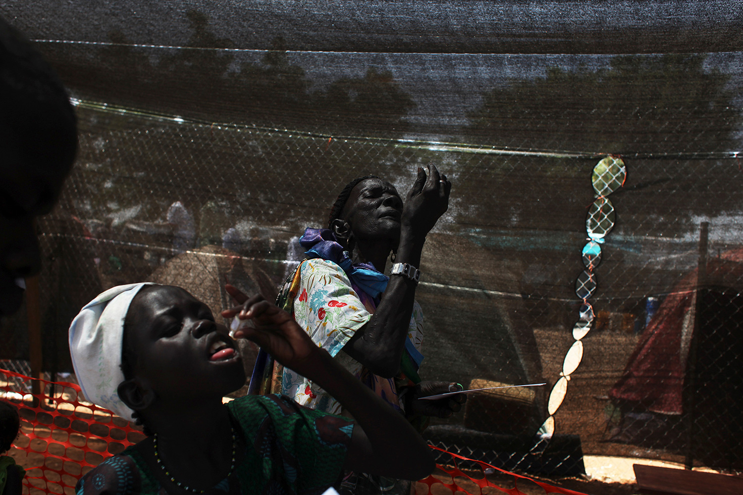 The photo shows two people, heads back, putting drops in their own mouths.