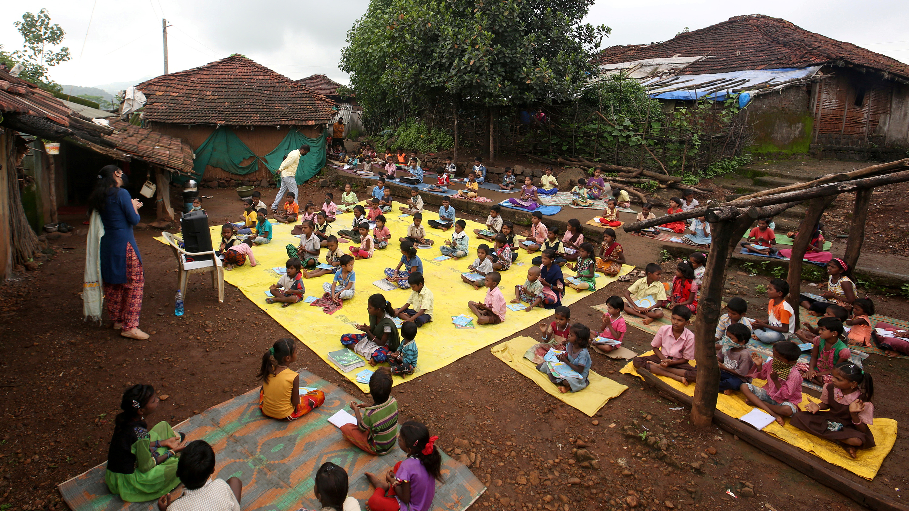 Picture shows an outdoor area with a huge group of kids seated at a safe distance from one another.