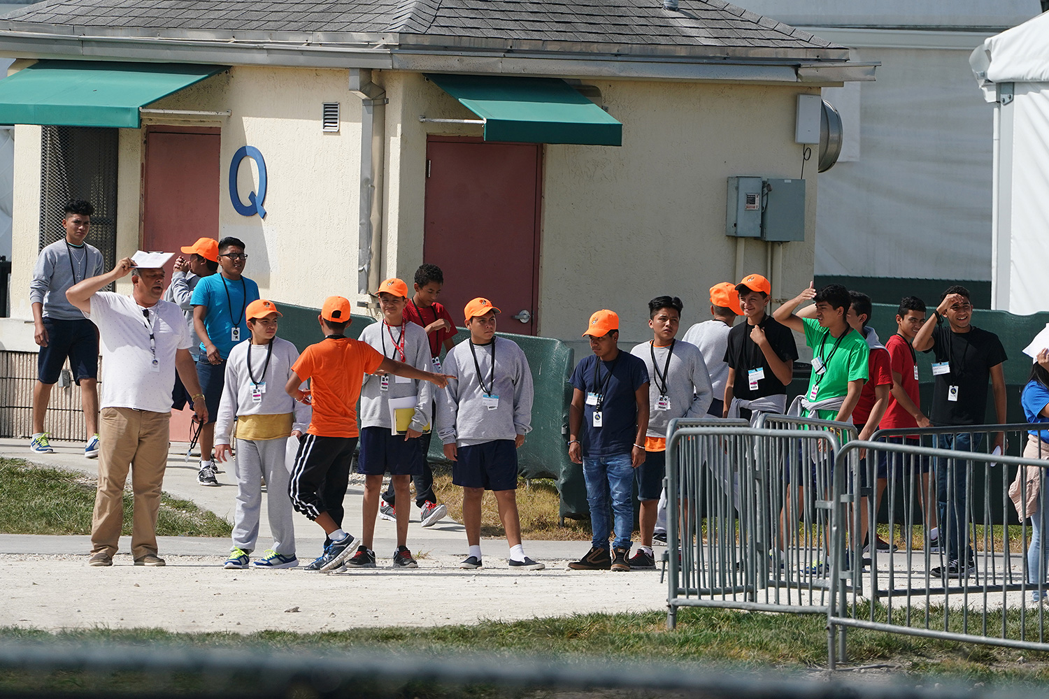 The photo shows a group of children, all with orange hats, standing in a line.