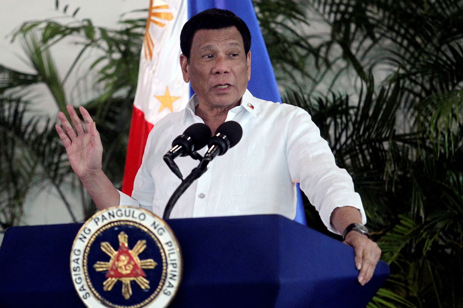 The photo shows the president at a podium speaking into a microphone and gesturing with his hand.