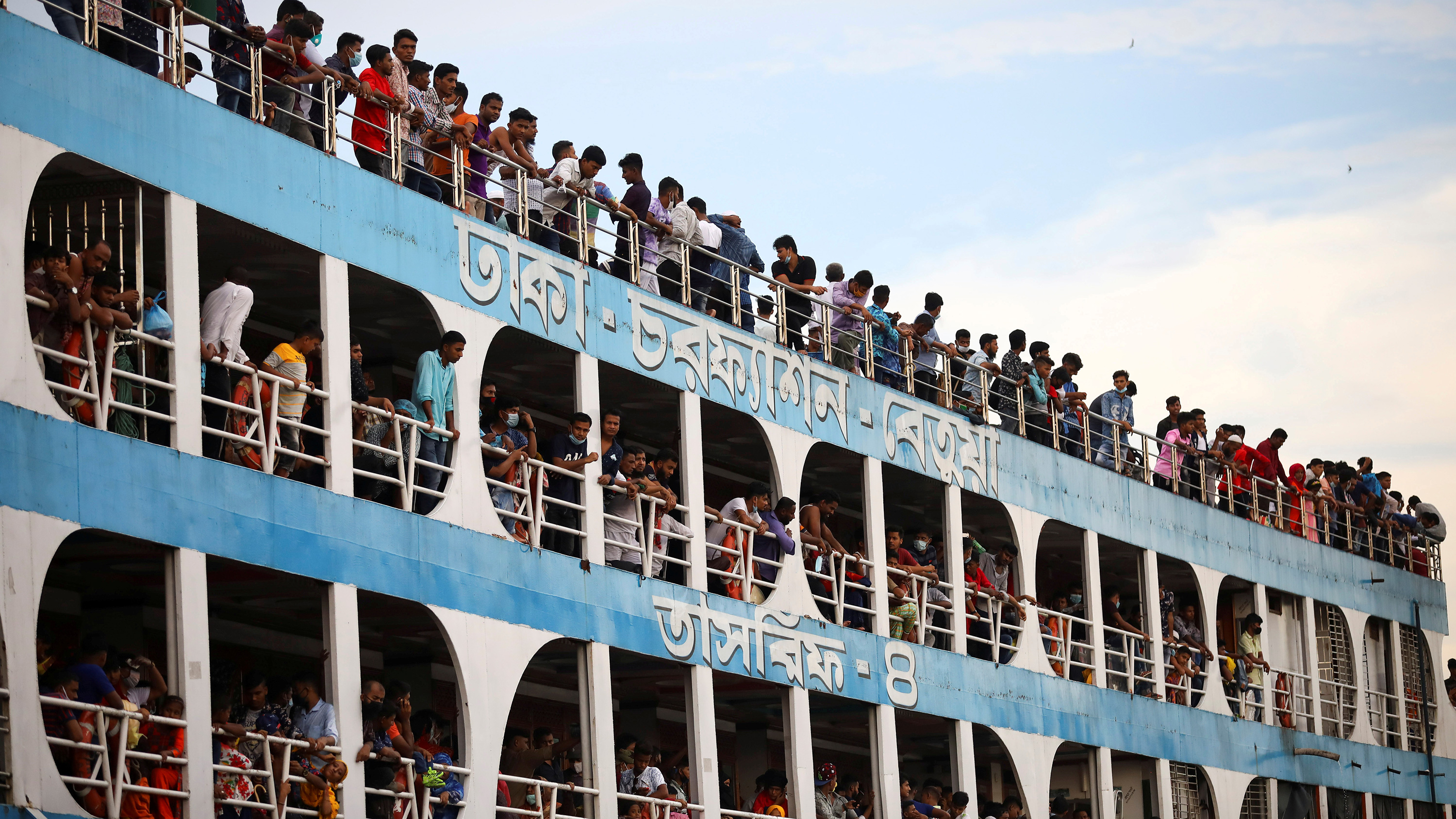 The photo shows the ferry from the side with all balconies jammed with people, most not wearing masks.