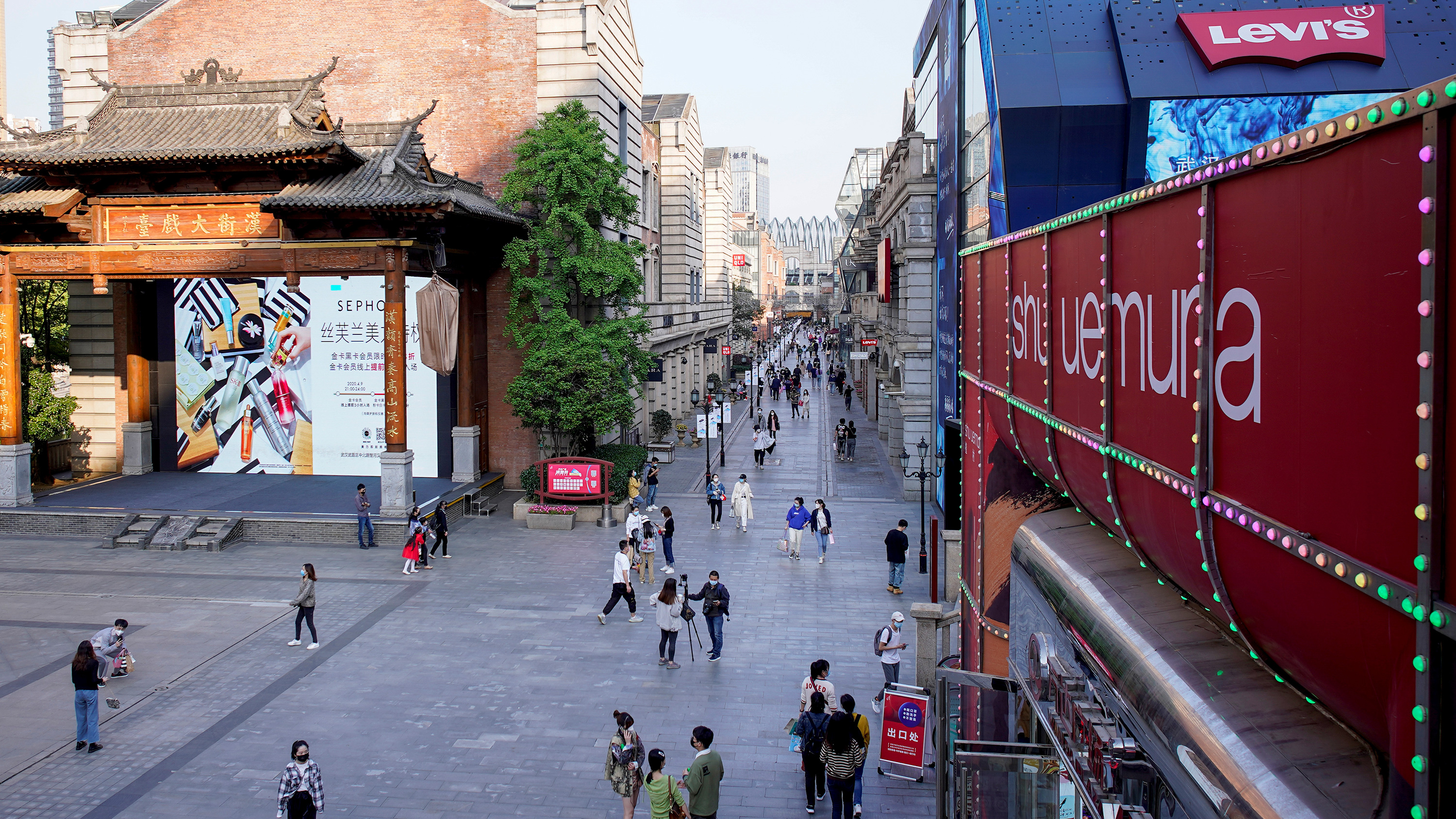 This photo shows a shopping complex in Wuhan, China, on April 9, 2020. The photo shows a street from above sparsely crowded with people.