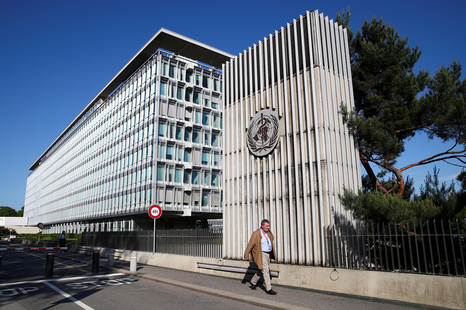 The photo shows the buildings with the official in front on a brilliant spring day with a clear blue sky.