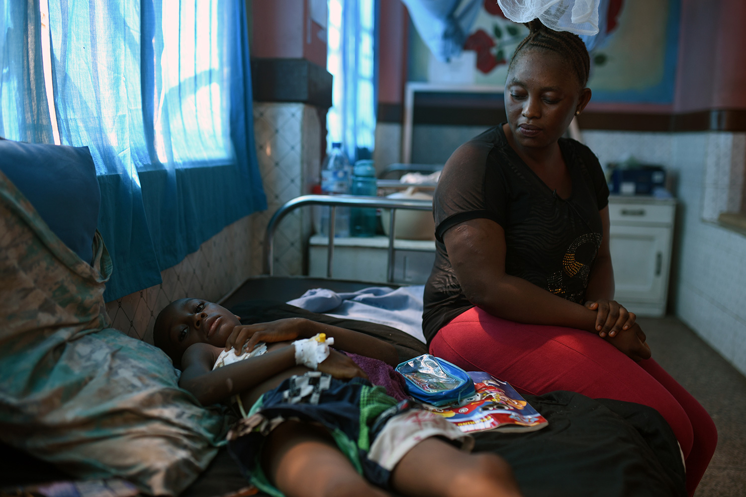 Picture shows the mother with child on a bed in a darkened ward.