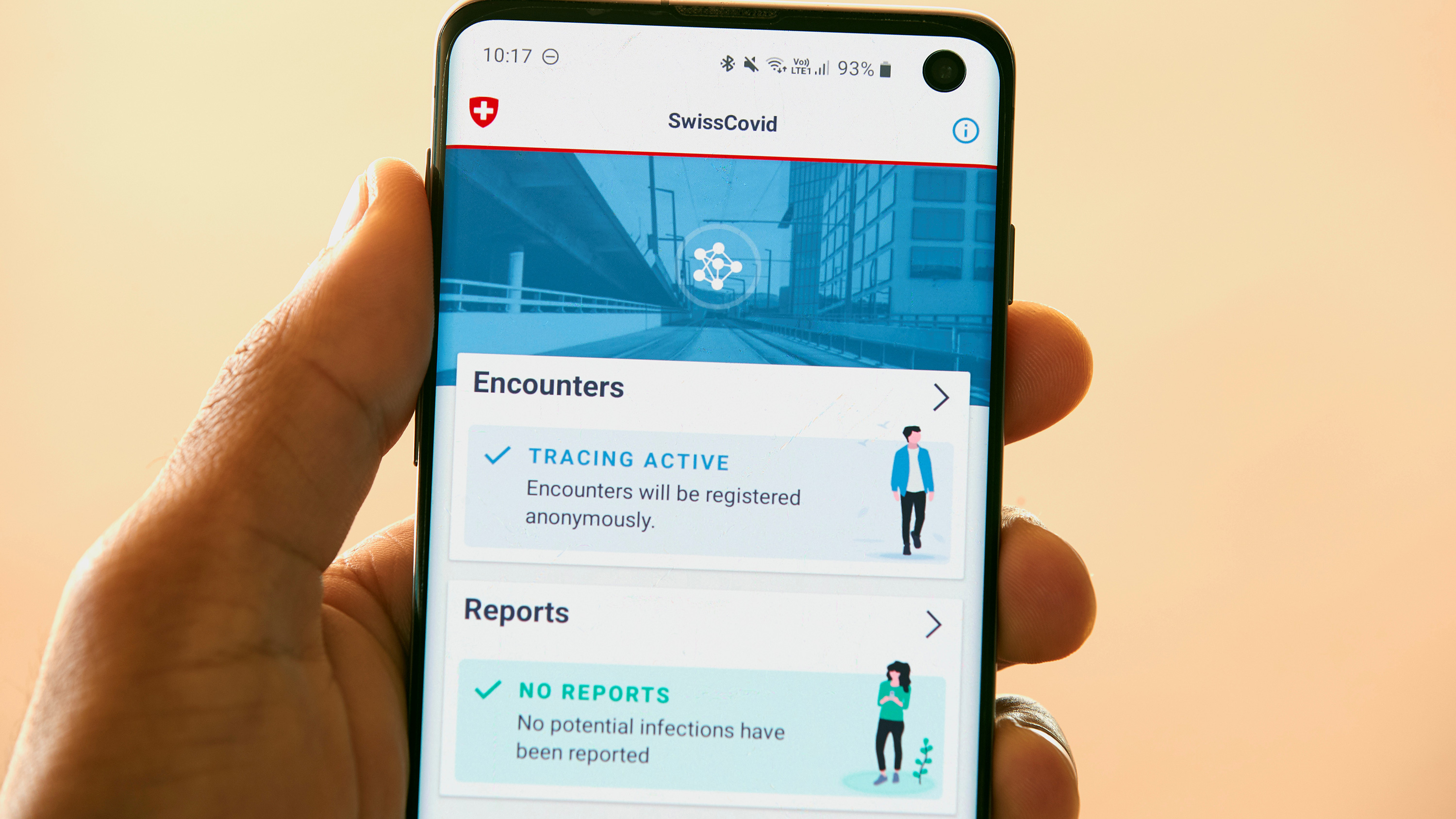 The photo shows a hand holding a device on which the app is displayed.