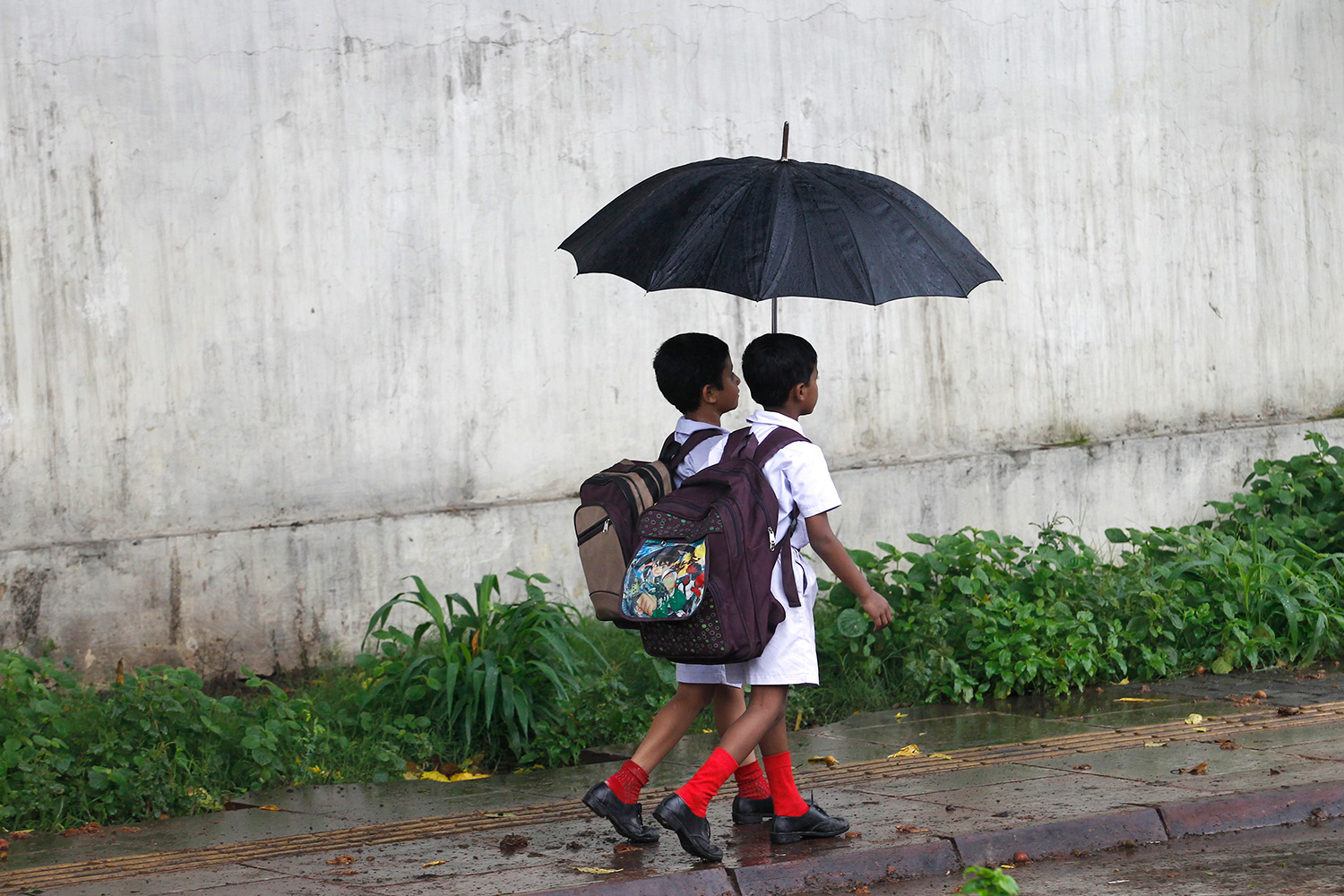 The photo shows two small children with umbrellas walking through the rain.