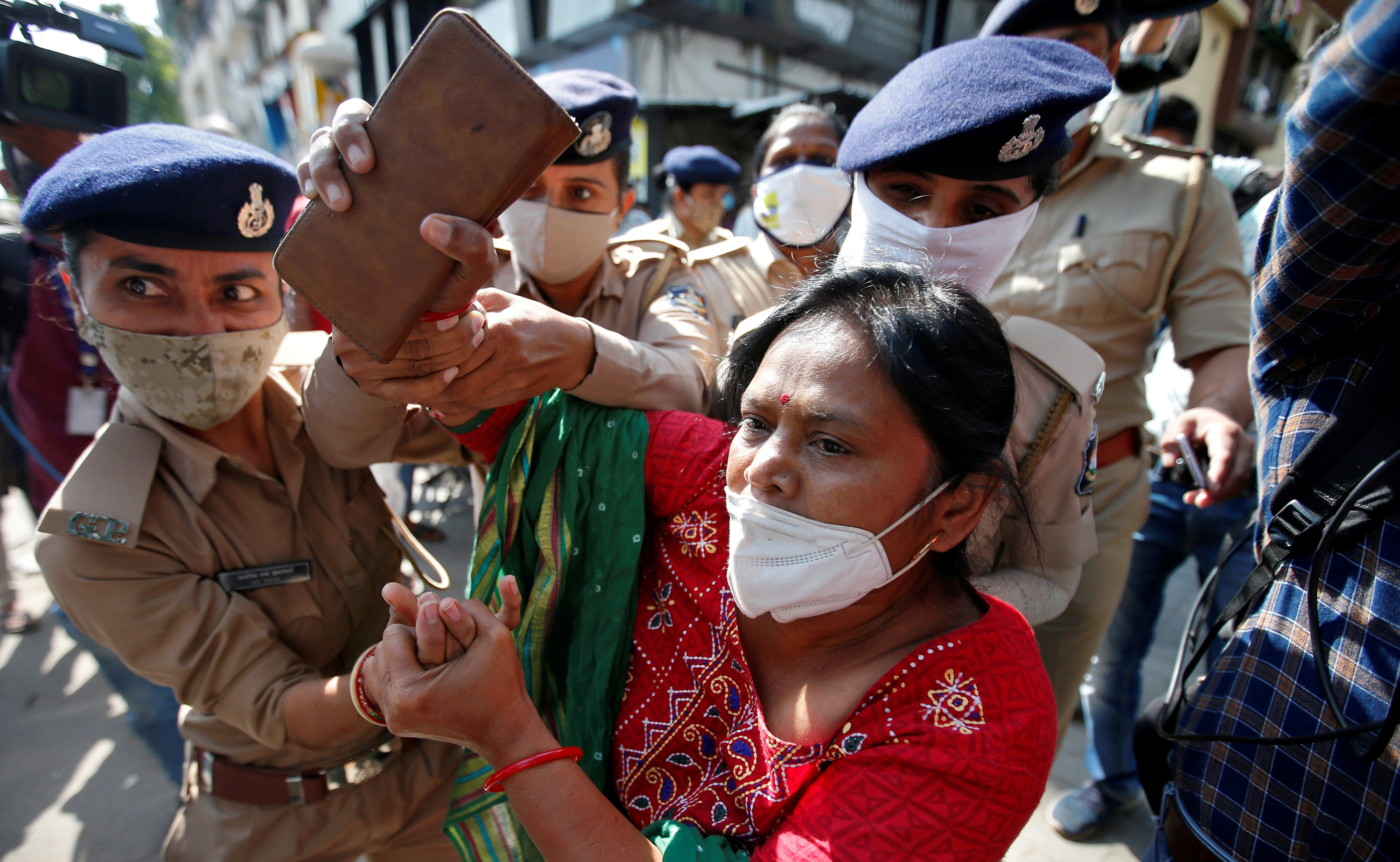 The photo shows a woman being led away by uniformed officers, who are grabbing her hands.