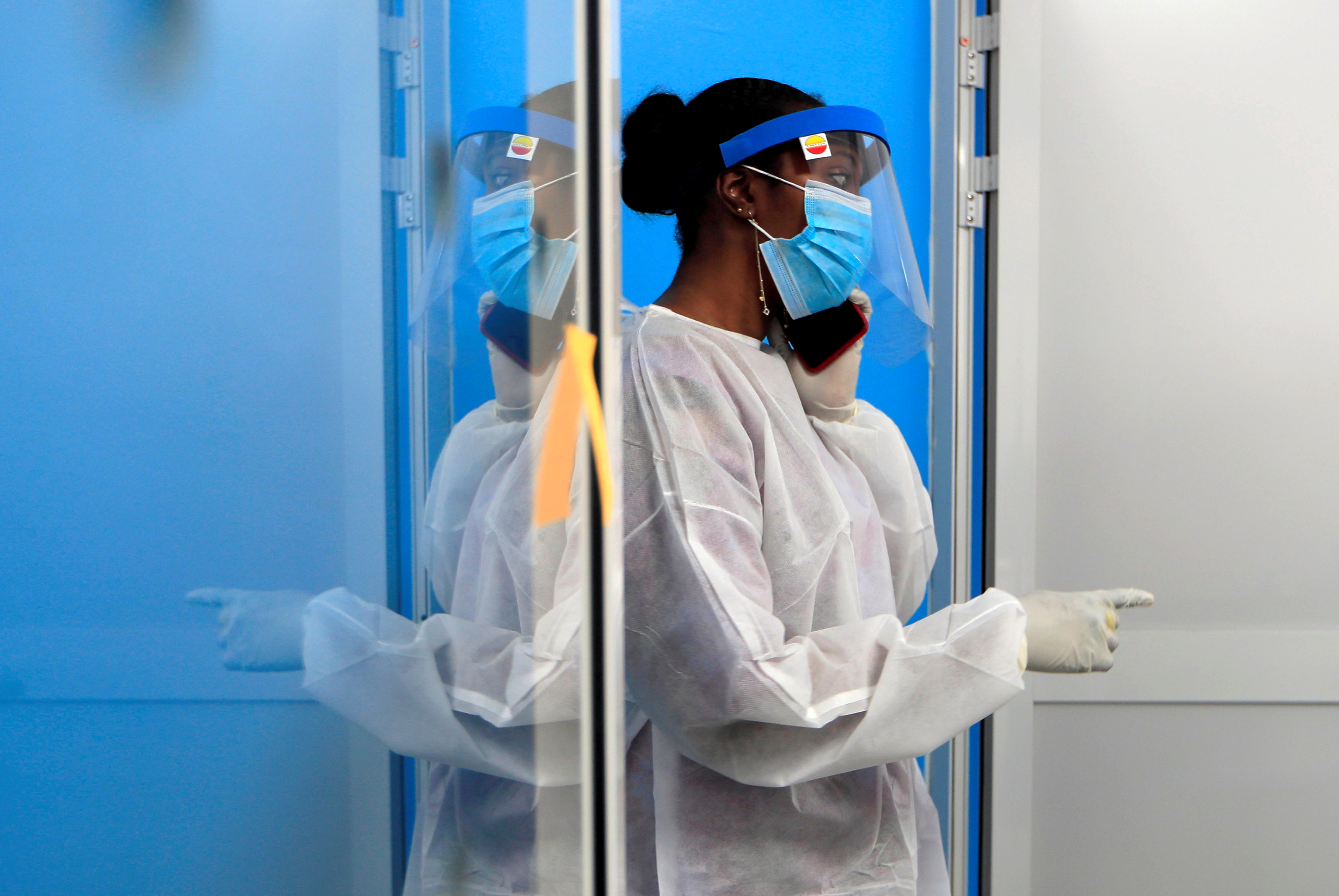 A health-care worker wearing protective gear talks on a mobile phone at a testing center for the coronavirus disease (COVID-19) of the Institute for Health Research, Epidemiological Surveillance and Training (IRESSEF), in Dakar, Senegal July 24, 2020. 