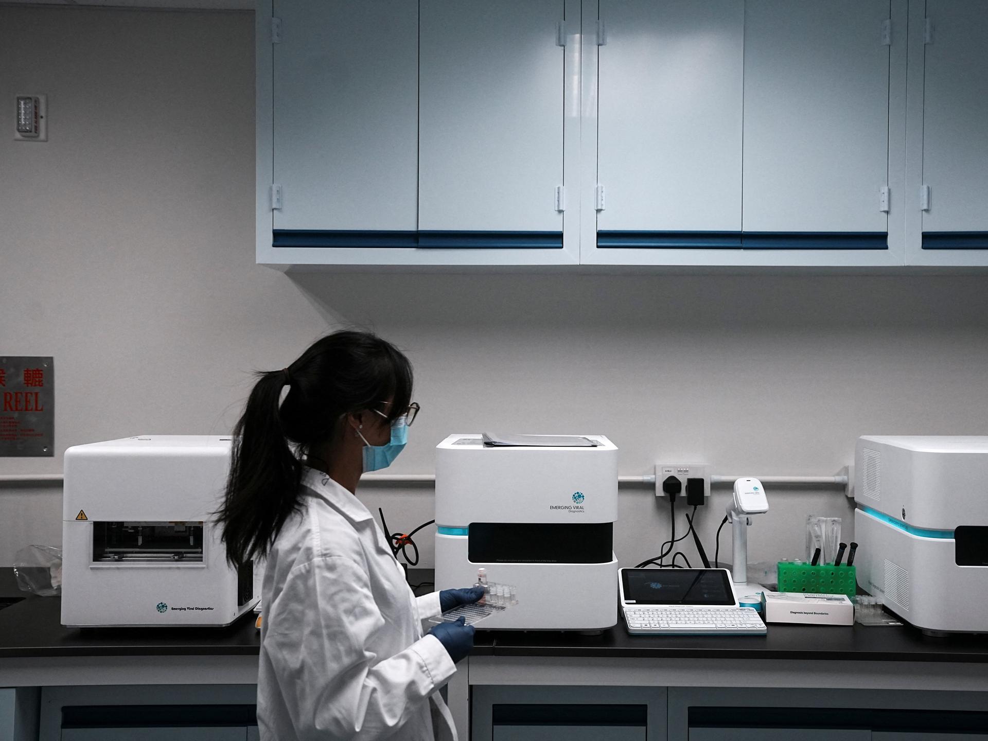 A staff member walks past the machines used for pathogen detection, at a laboratory inside the Emerging Viral Diagnostics office, in Hong Kong, China, on March 13, 2023