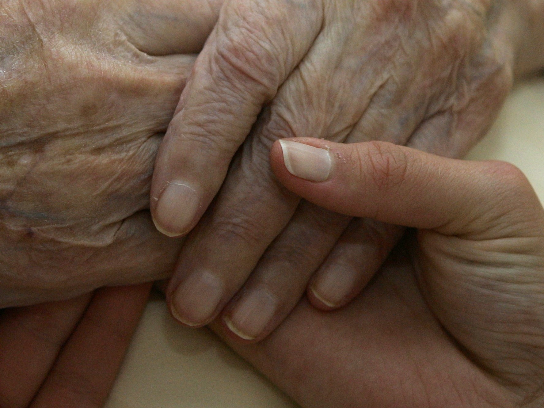 A caregiver holds the hands of an elderly woman, in Planegg, Germany, on June 19, 2007.