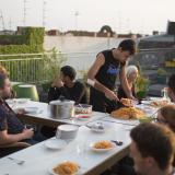 People seeking refuge in a new country live alongside German residents in the "Sharehaus Refugio" community in Berlin, Germany (2015). Neighbors in the five-story, century-old building meet for meals on the rooftop garden.