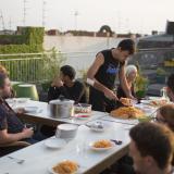 People seeking refuge in a new country live alongside German residents in the "Sharehaus Refugio" community in Berlin, Germany (2015). Neighbors in the five-story, century-old building meet for meals on the rooftop garden.