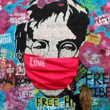 A woman wearing a face mask during the COVID-19 pandemic touches the legendary graffiti-covered John Lennon Wall in Prague, Czech Republic, on April 6, 2020.