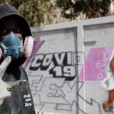 Serigne Boye aka Zeus, a street artist from RBS crew, flashes a peace sign as he stands beside his mural meant to encourage people to protect themselves during the coronavirus outbreak in Dakar, Senegal, on March 25, 2020.