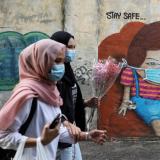 Women wearing protective masks walk past street art encouraging people to "stay safe" amid the coronavirus pandemic in Kuala Lumpur, Malaysia, on September 18, 2020.