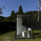 women's restroom is a glass cubicle with a fully functioning toilet that stands in a garden,