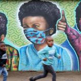 Boys run past a mural by graffiti artist Senzart911 during the COVID outbreak, in Kliptown, the oldest residential district of Soweto, South Africa, on October 27, 2021.