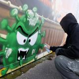 Artist David "S.I.D." Perez spray paints an image representing two vaccines fighting against a virus, in Gland, Switzerland, on December 3, 2020.