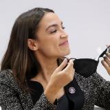 U.S. Representative Alexandria Ocasio-Cortez holds her face mask as she addresses a panel at COP26 on November 9, 2021.