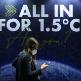 A delegate walks past an "all in for 1.5" sign during the climate conference. The phrase refers to the 2015 Paris Agreement goal to limit global warming to 1.5 degrees Celsius.